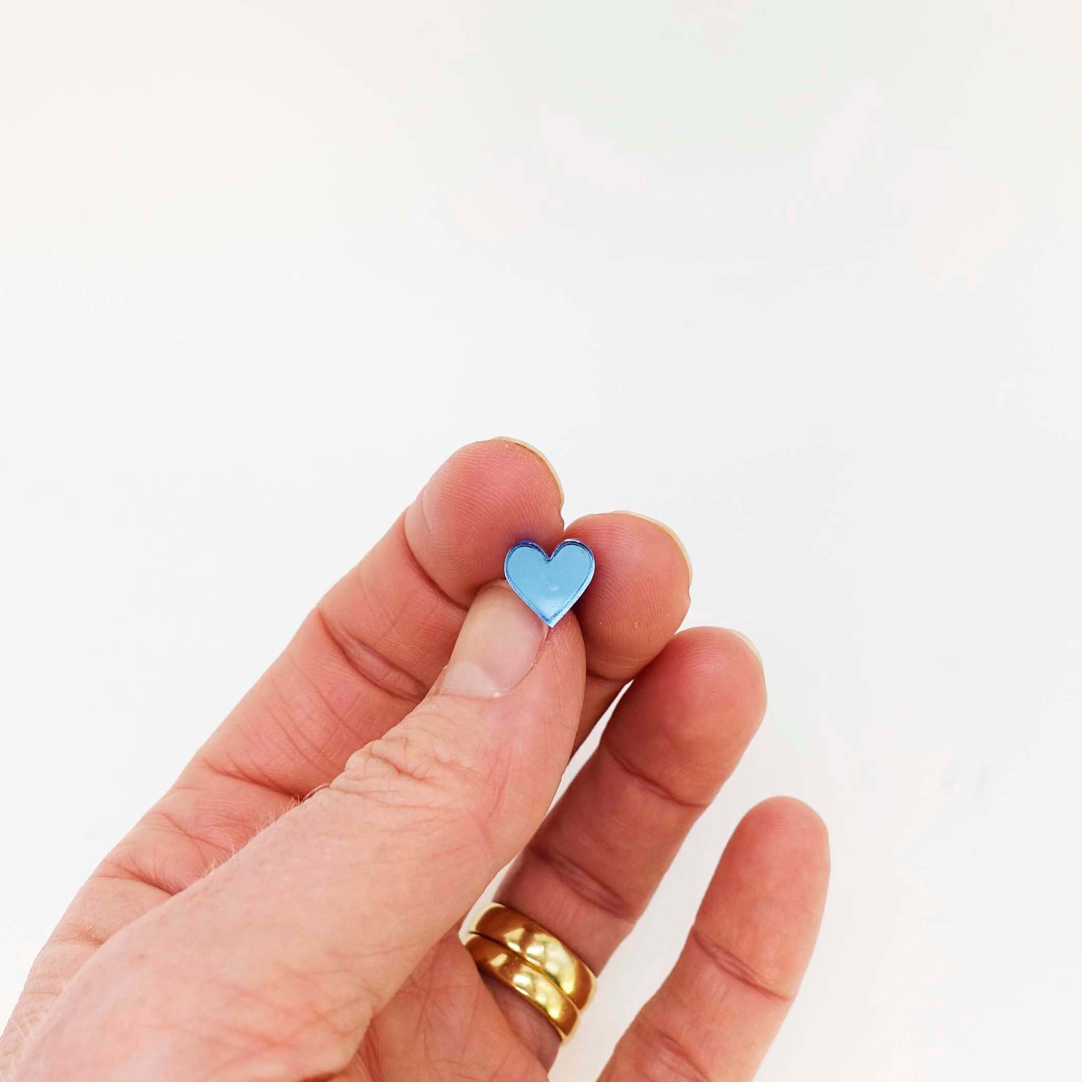 My hand holding a small sky mirror heart earring for scale.
