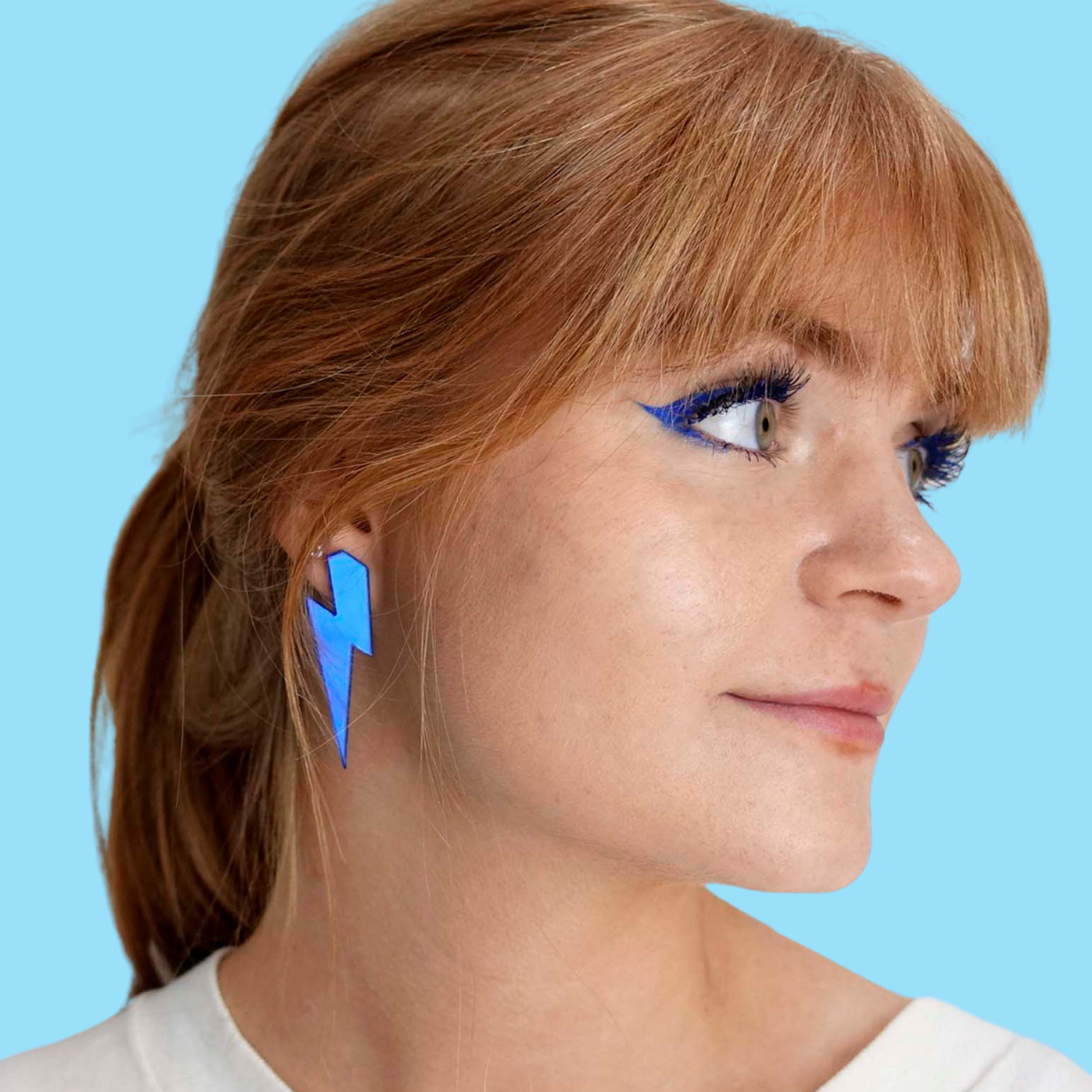 Eliza wears large Lightning Bolt earrings in sky mirror.
