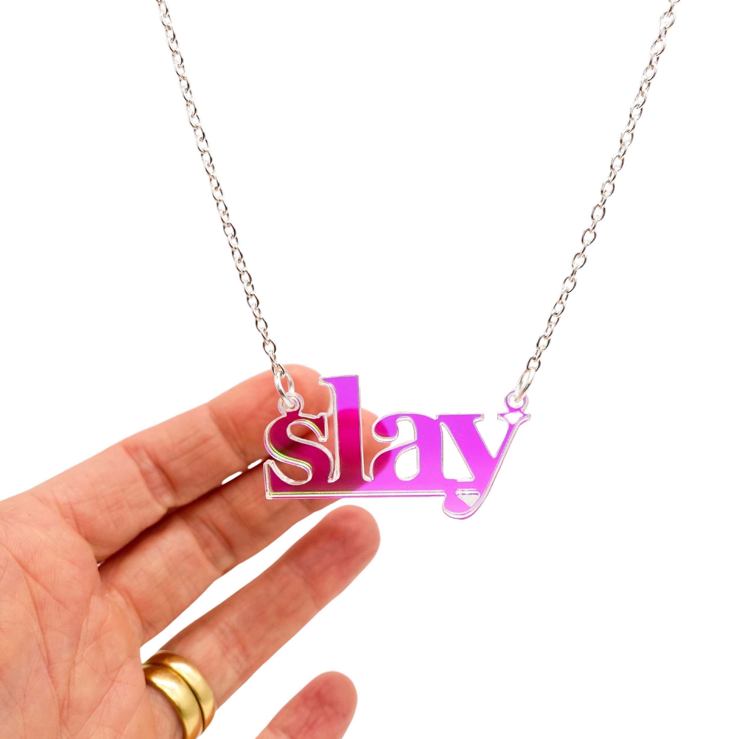 Slay necklace in iridescent on a silver chain shown hanging against a white background. Designed by Sarah Day for Wear and Resist. £2 goes to Women for Refugee Women charity.