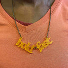 A close up of a member of Women for Refugee Women wearing a sunflower frost Hold Fast necklace.