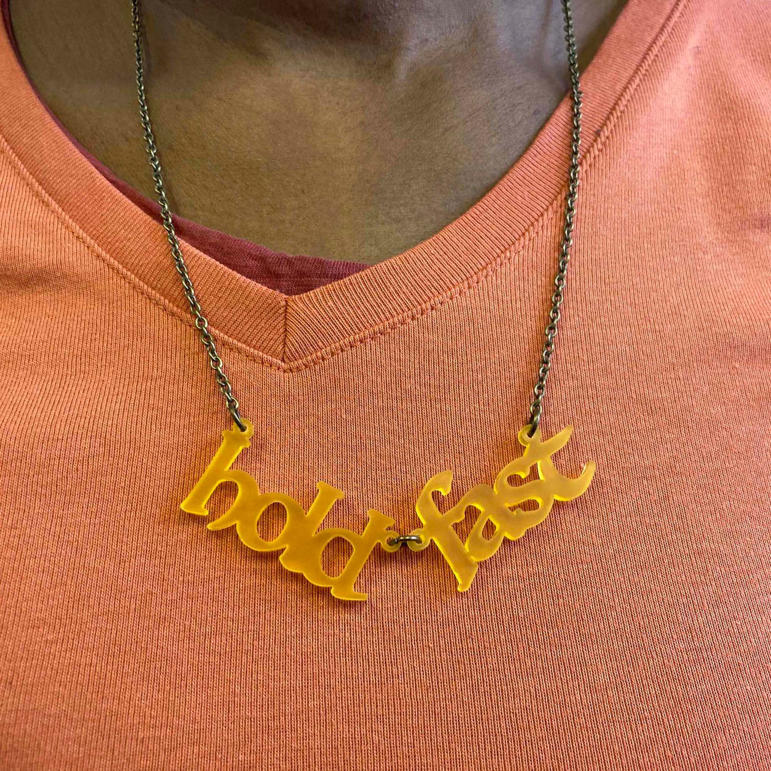 A close up of a member of Women for Refugee Women wearing a sunflower frost Hold Fast necklace.