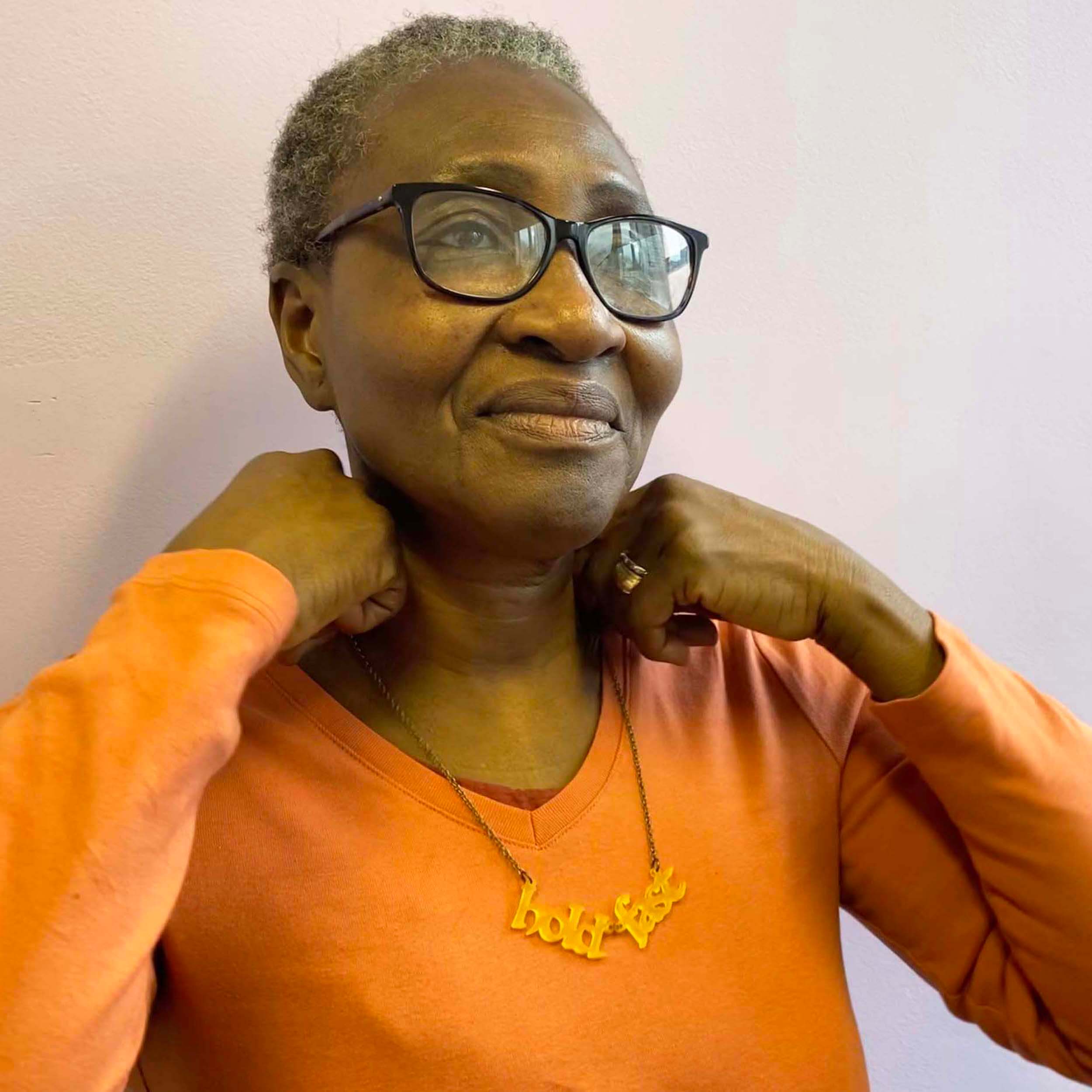 A member of Women for Refugee Women wears a sunflower yellow  frost Hold Fast necklace, designed by Sarah Day for Wear and Resist. 