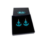 Medium anchor earrings in teal etched with the words 'courage' on one and 'hold fast' on the other. Shown in a Wear and Resist gift box.