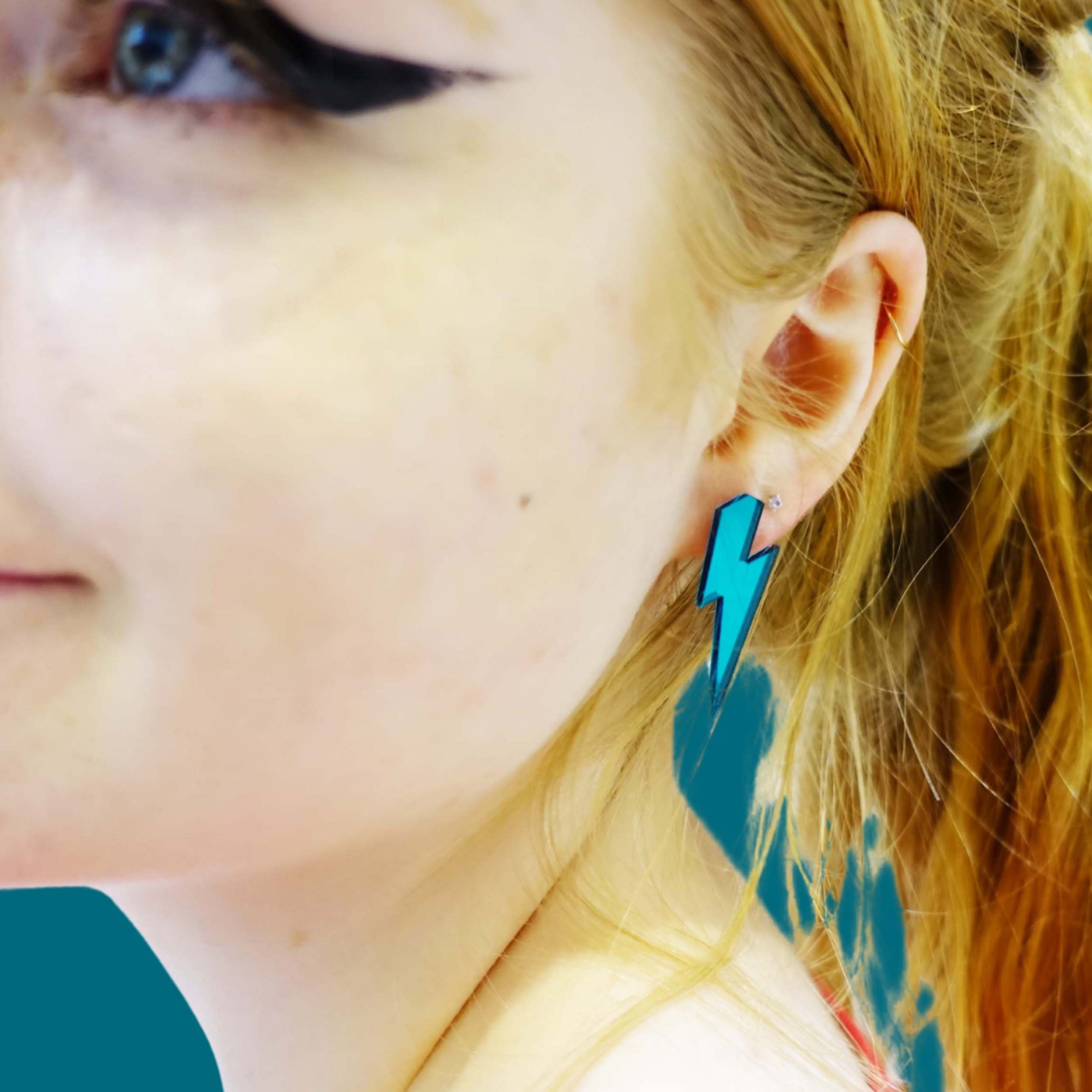 Eliza wears medium Lightning Bolt earrings in teal mirror.