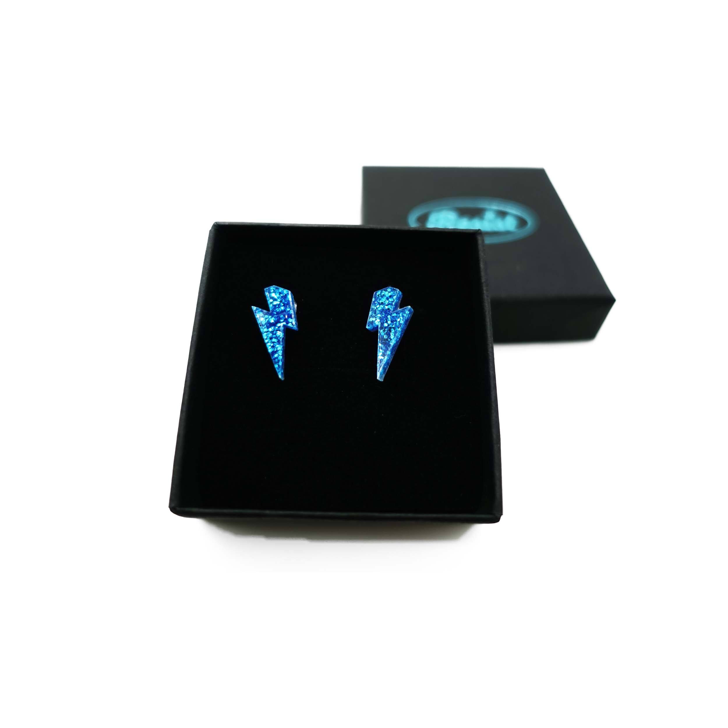 Tiny Lightning Bolt earrings in blue glitter, shown in a Wear and Resist gift box.