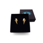 Tiny Lightning Bolt earrings in gold glitter, shown in a Wear and Resist gift box.