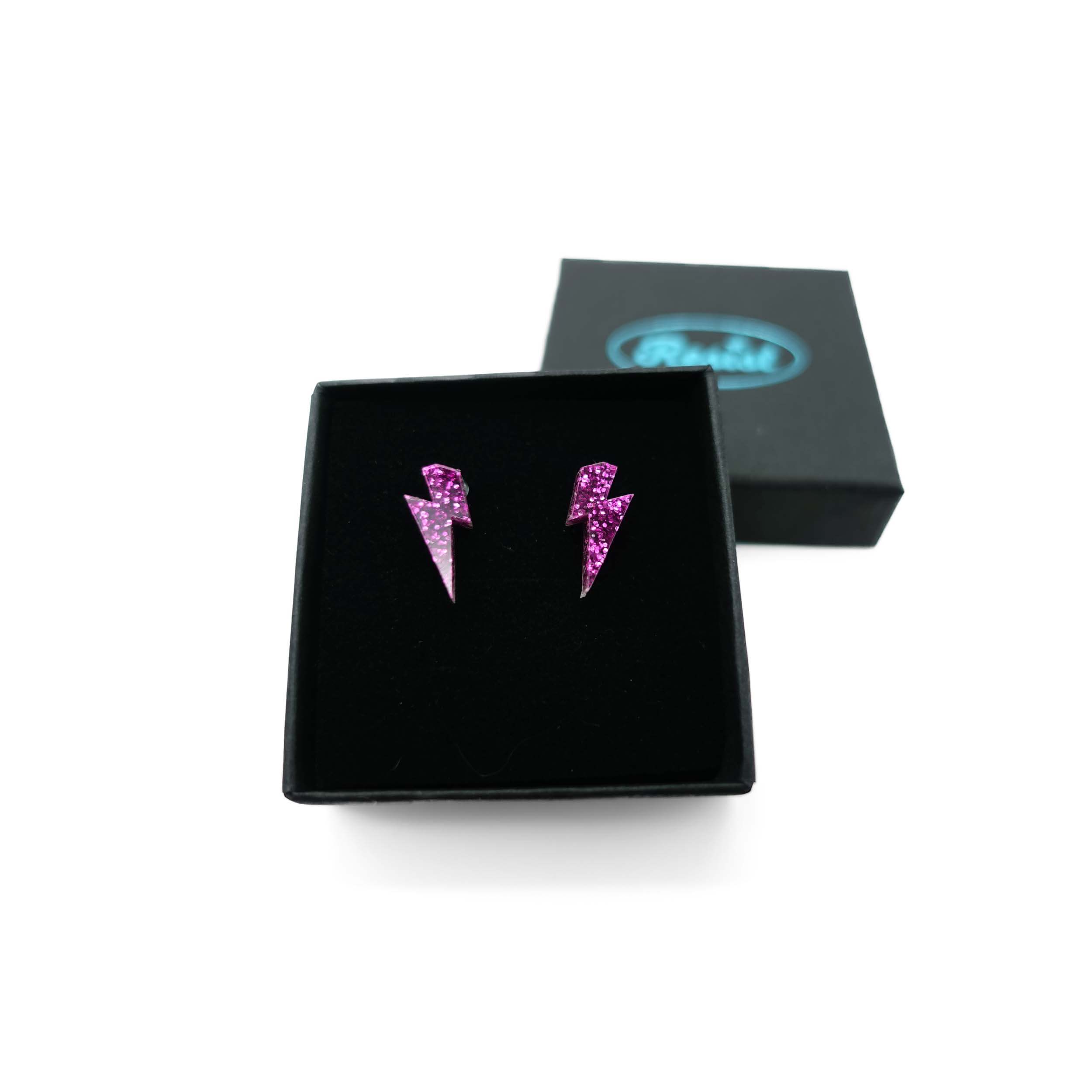 Tiny Lightning Bolt earrings in purple glitter, shown in a Wear and Resist gift box.