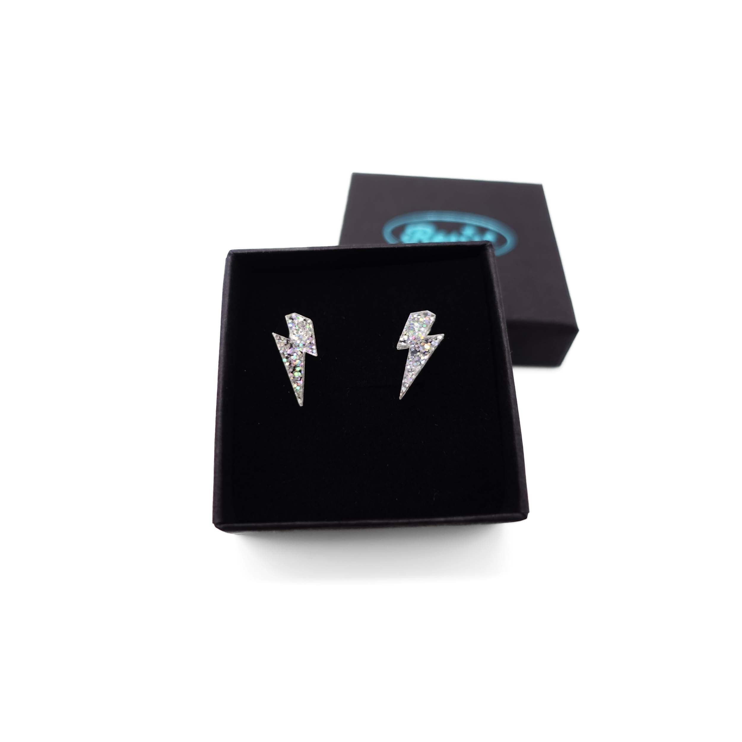 Tiny Lightning Bolt earrings in silver glitter, shown in a Wear and Resist gift box.