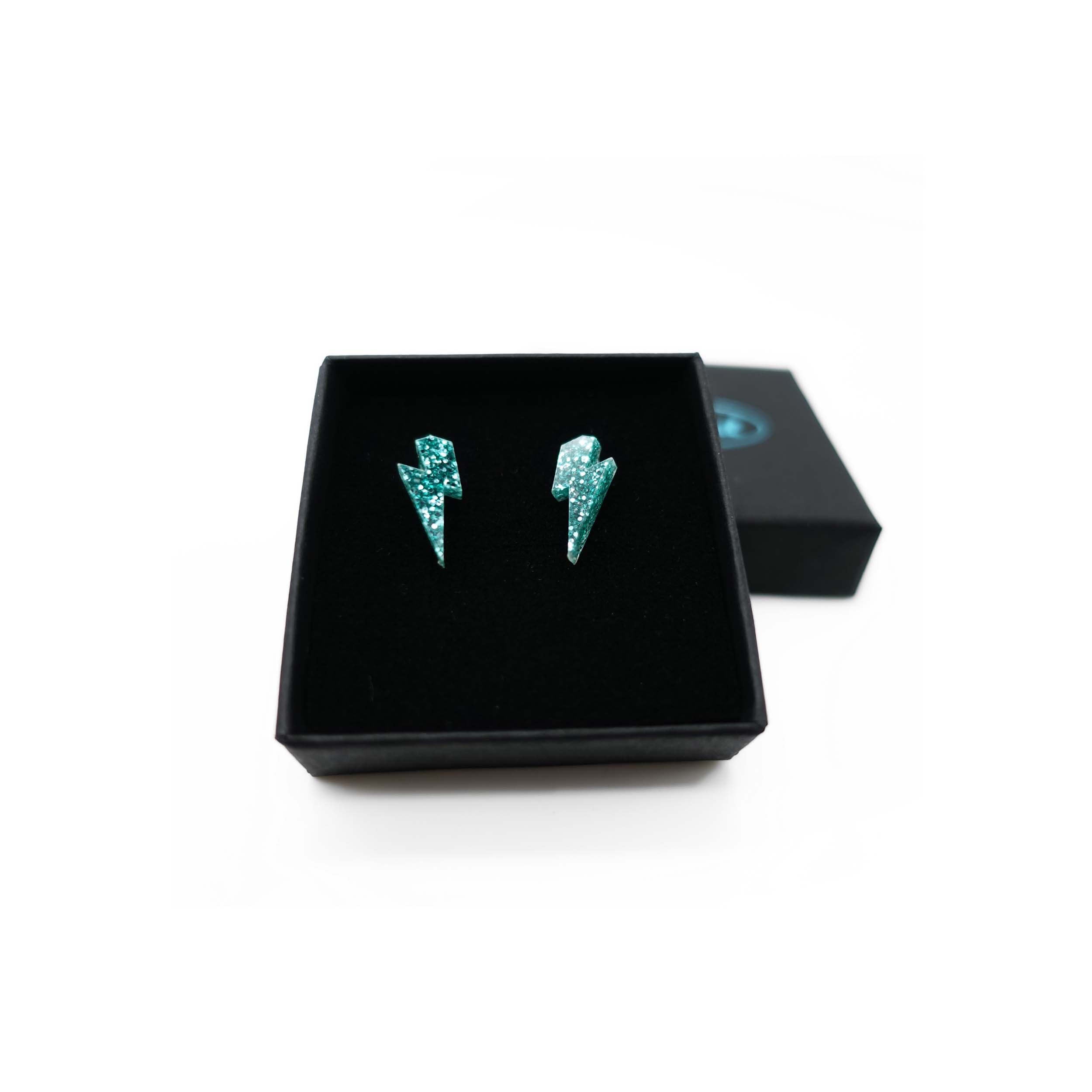 Tiny Lightning Bolt earrings in teal glitter, shown in a Wear and Resist gift box.