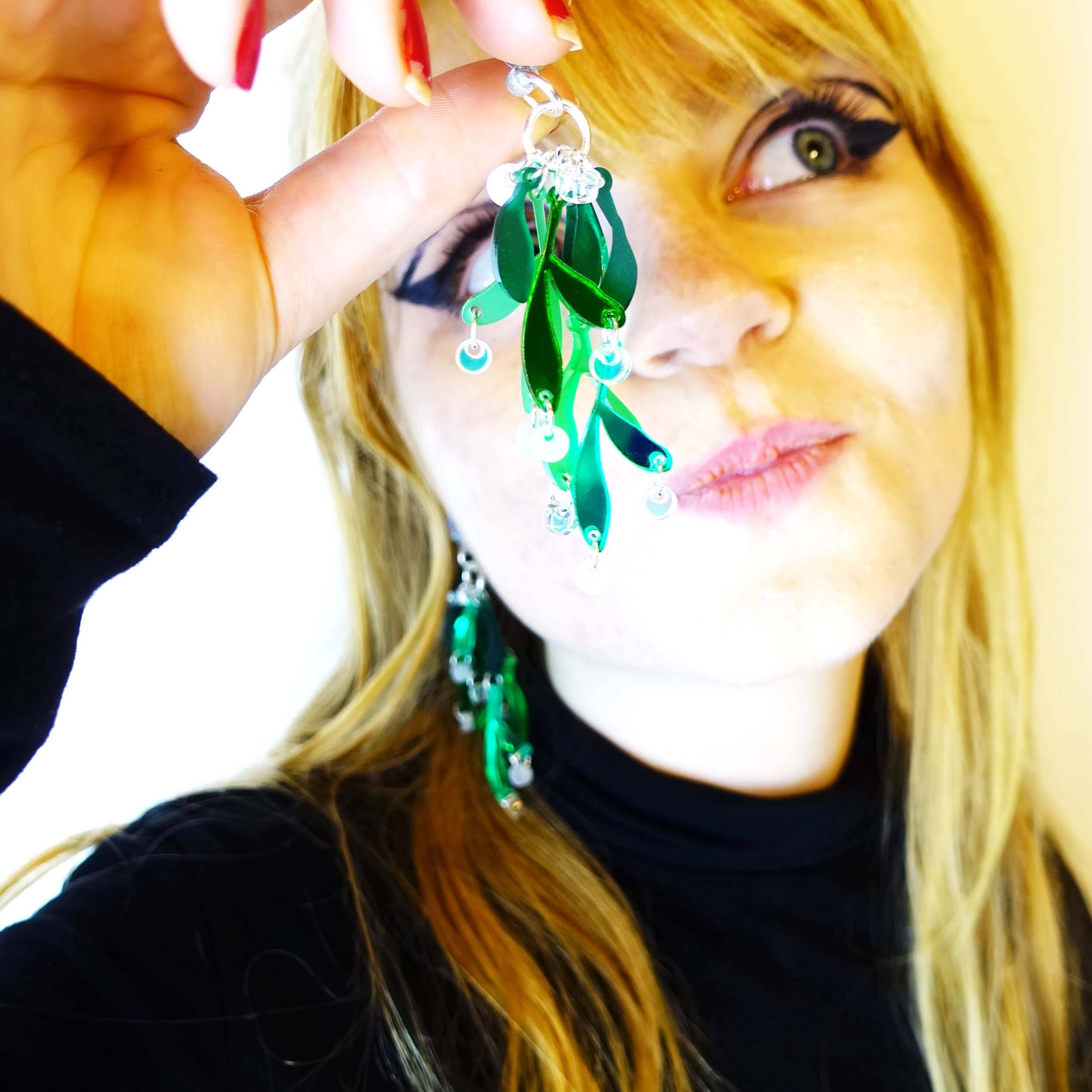 Eliza holds up a mistletoe earring ready for a kiss.
