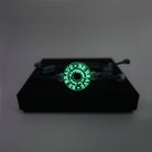Hand-tied friendship style bracelet inscribed with 'Be brave. It's supposed to be hard,' in glow in the dark pigment. Shown on a Wear and Resist gift box.