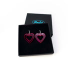 Big heart hoops in neon pink on silver hoops, shown in a Wear and Resist gift box.