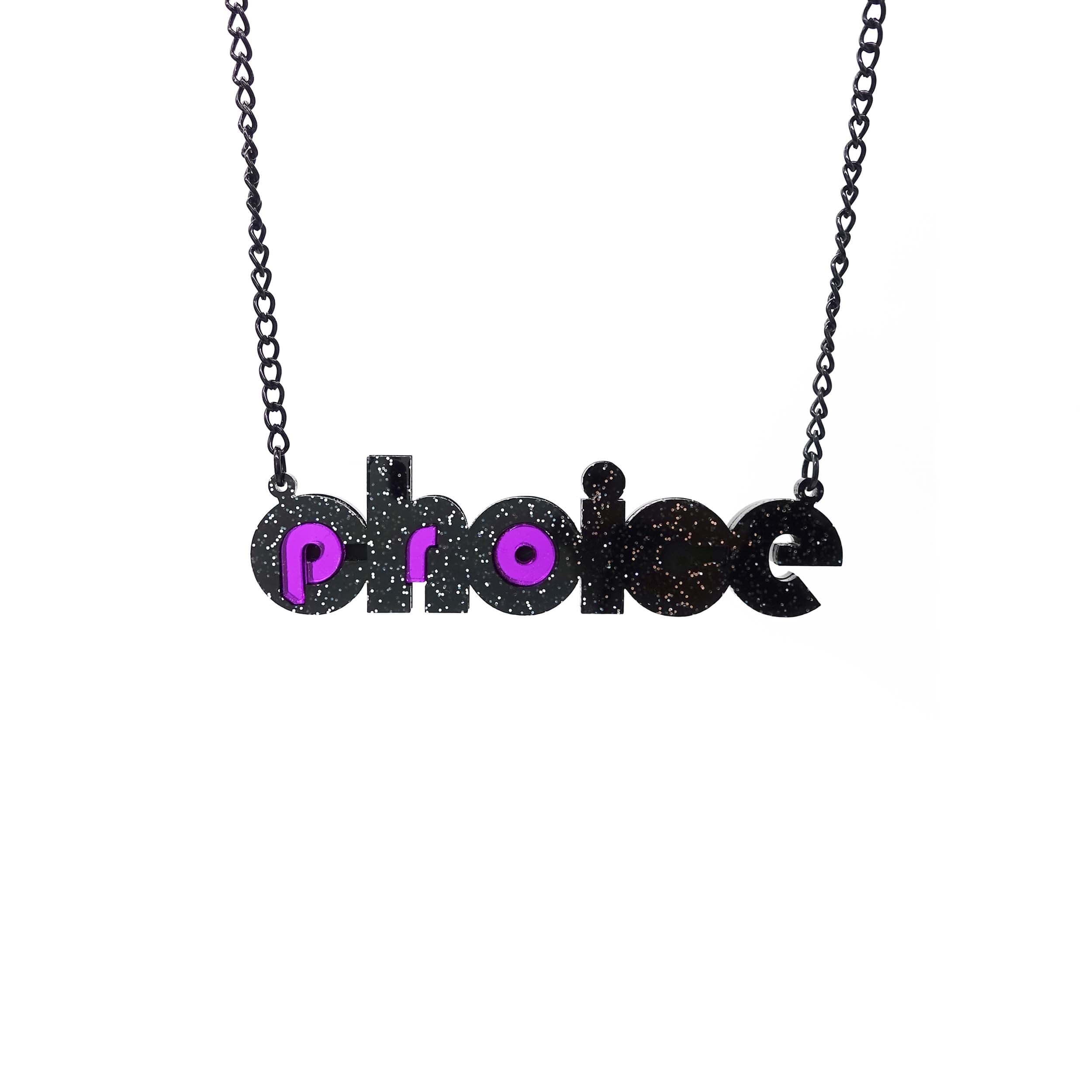 Black glitter and purple mirror Pro-choice necklace, shown hanging on black chain, designed by Sarah Day for Wear and Resist. £2 goes to Alliance for Choice who campaign  for Free, Safe and Legal abortions for anyone who needs them.