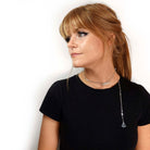 The Have a Word with Yourself design on a silver-plated paperclip chain as a shorter necklace, with the words 'hold fast' and 'courage' etched in glow-in-the-dark pigment. The tiny anchor charm is hanging down over her shoulder.