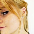 Eliza wears silver mirror tiny heart stud earrings.