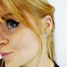 Eliza wears silver mirror tiny heart stud earrings.