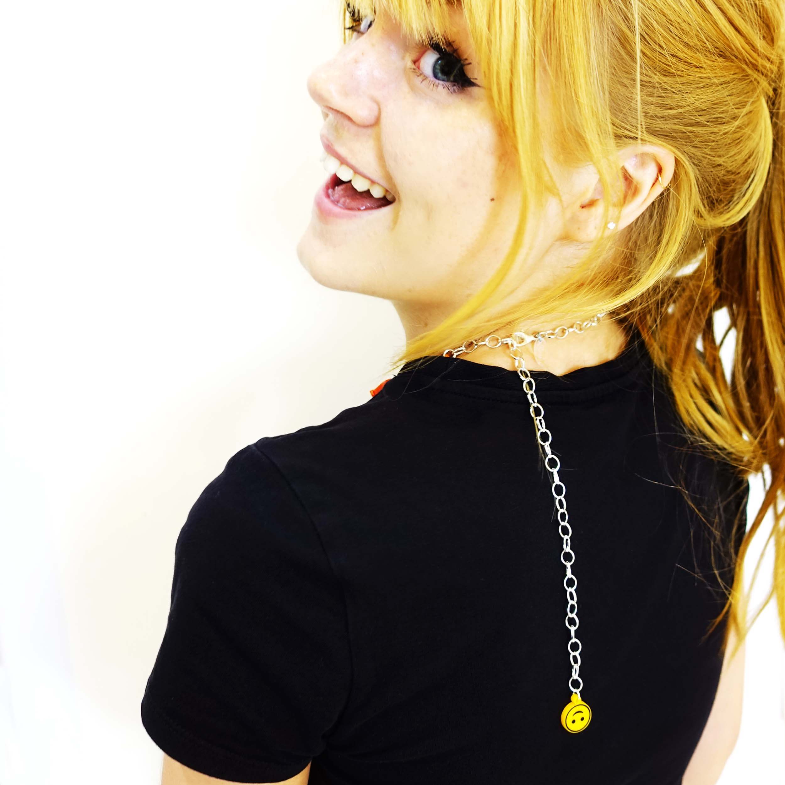 Eliza shown from the back, turning over her shoulder to show the necklace worn as a choker, with chain finished in upside down smiley face charm.