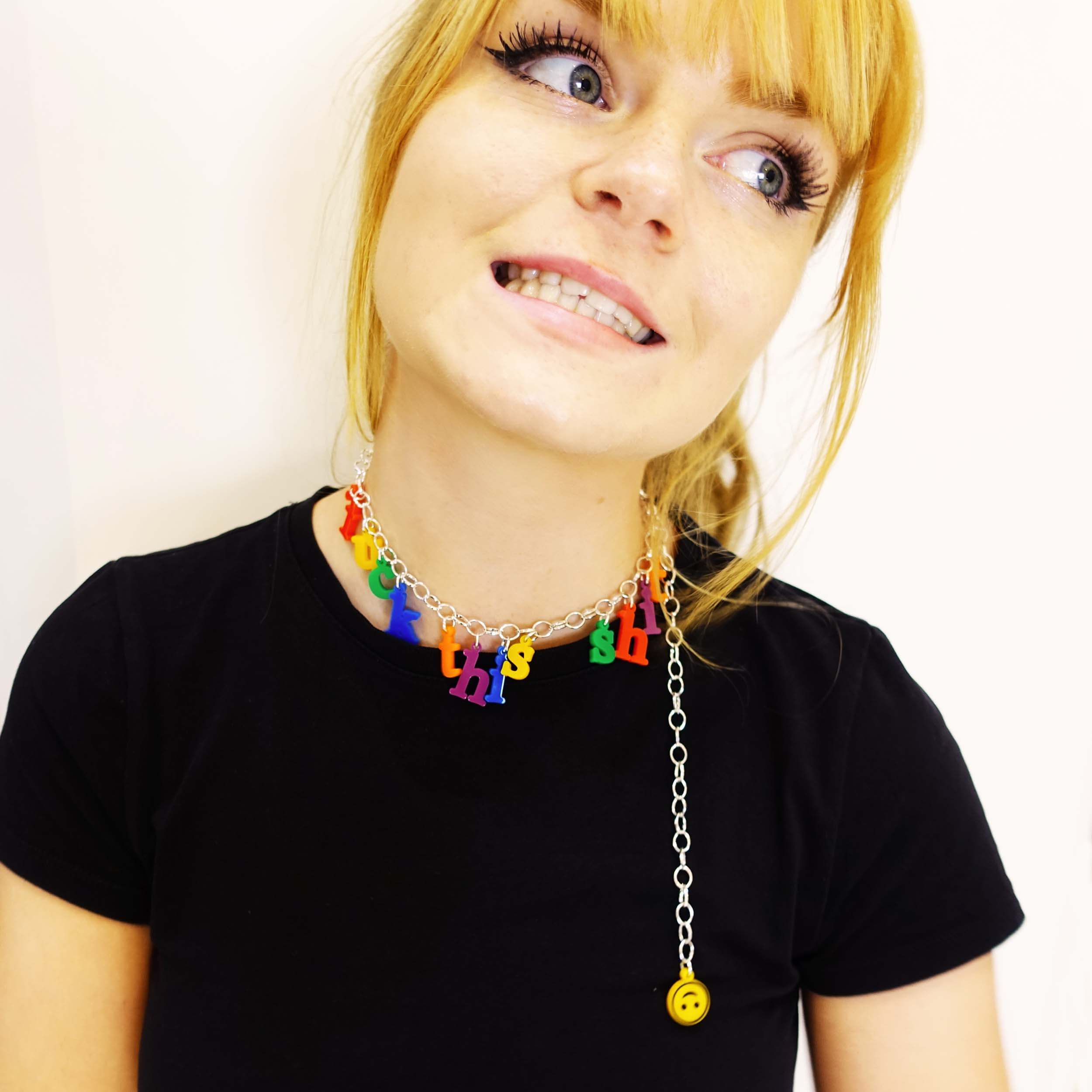 Eliza wears a F*ck this Sh*t necklace in retro alphabet letters as a choker with the upside down smiley face hanging down.