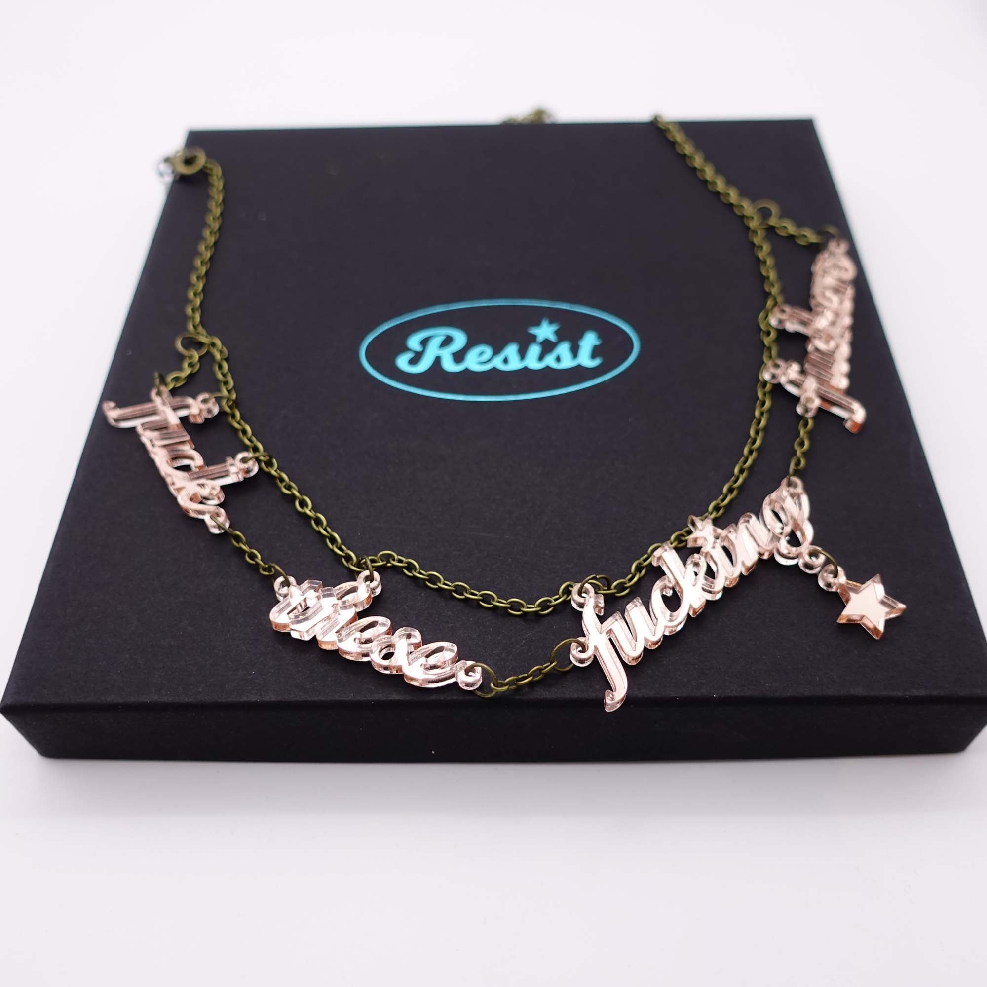 F*ck these F*cking F*ckers necklace in rose gold mirror, shown on top of a large Wear and Resist gift box.