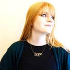 Eliza wears a gold glitter hope necklace designed by Sarah Day for Wear and Resist.