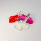 A group shot of all the three colours of simple heart earrings: neon pink, hot red and iridescent on silver-plated hoops.
