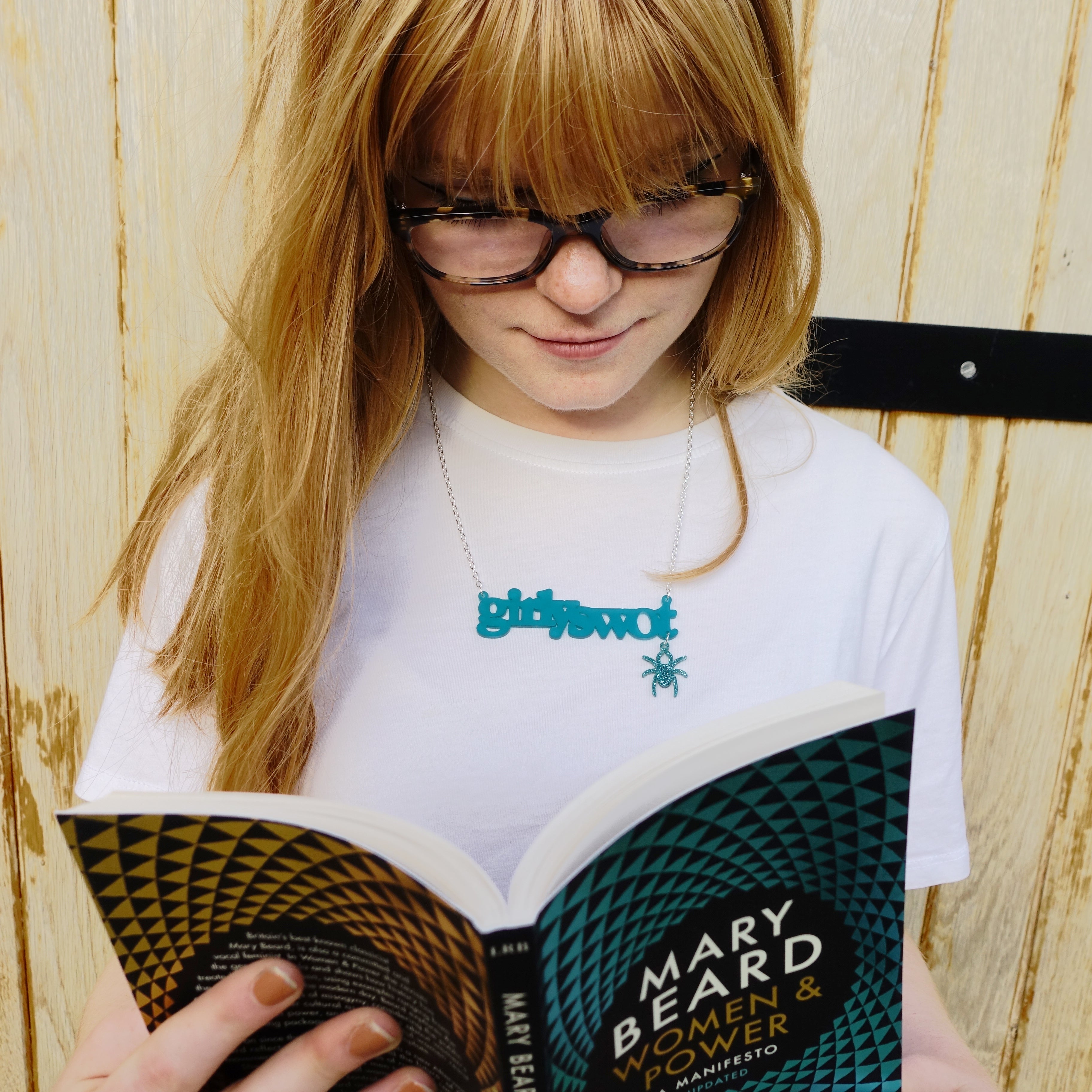 Eliza wears teal Girly swot necklace with hanging Lady Hale spider and reads Mary Beard's Women & Power. Girly swots unite!