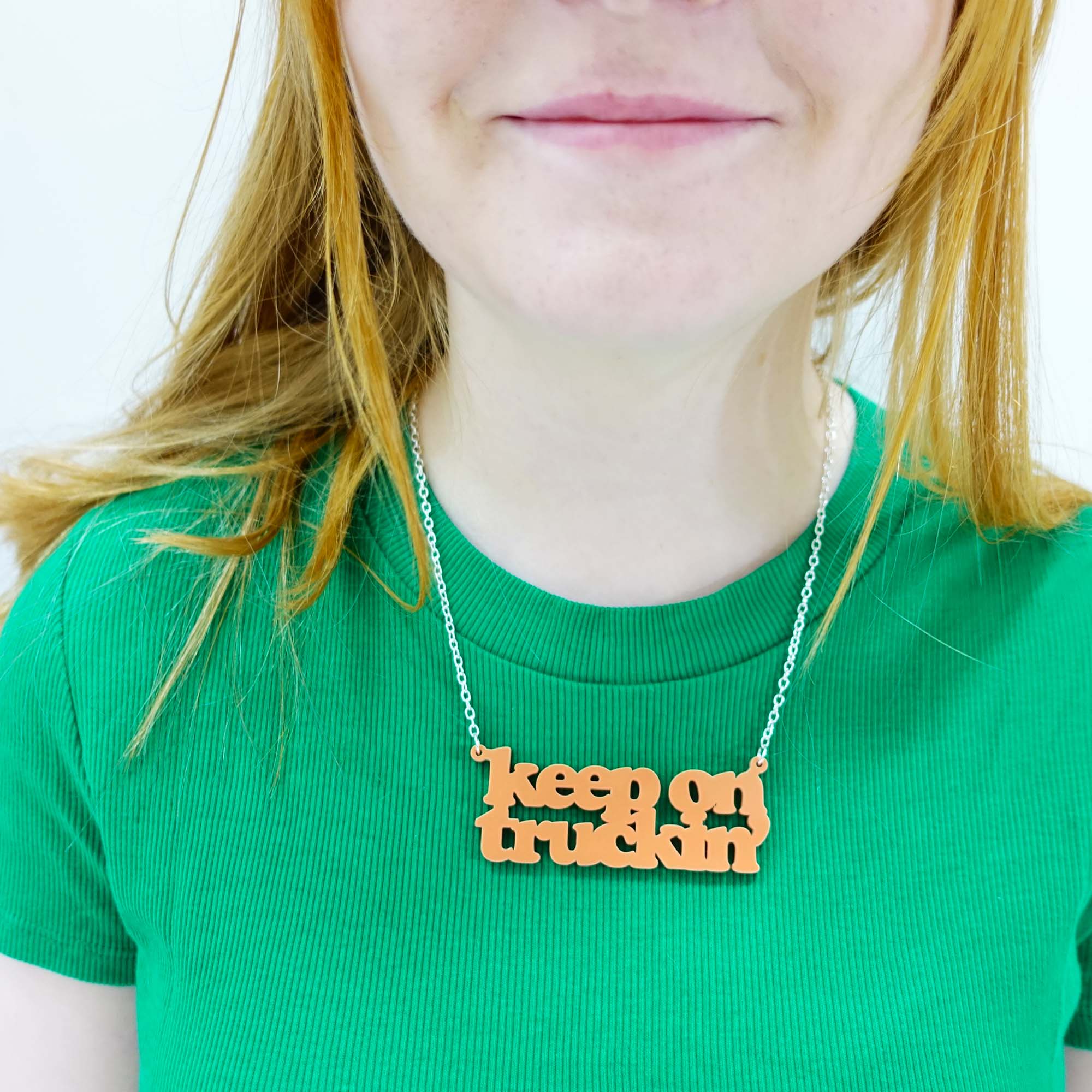 Eliza wears a Keep on Truckin' necklace in orange sherbet.