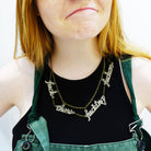 Eliza wears a bronze F*ck these F*cking F*ckers necklace.