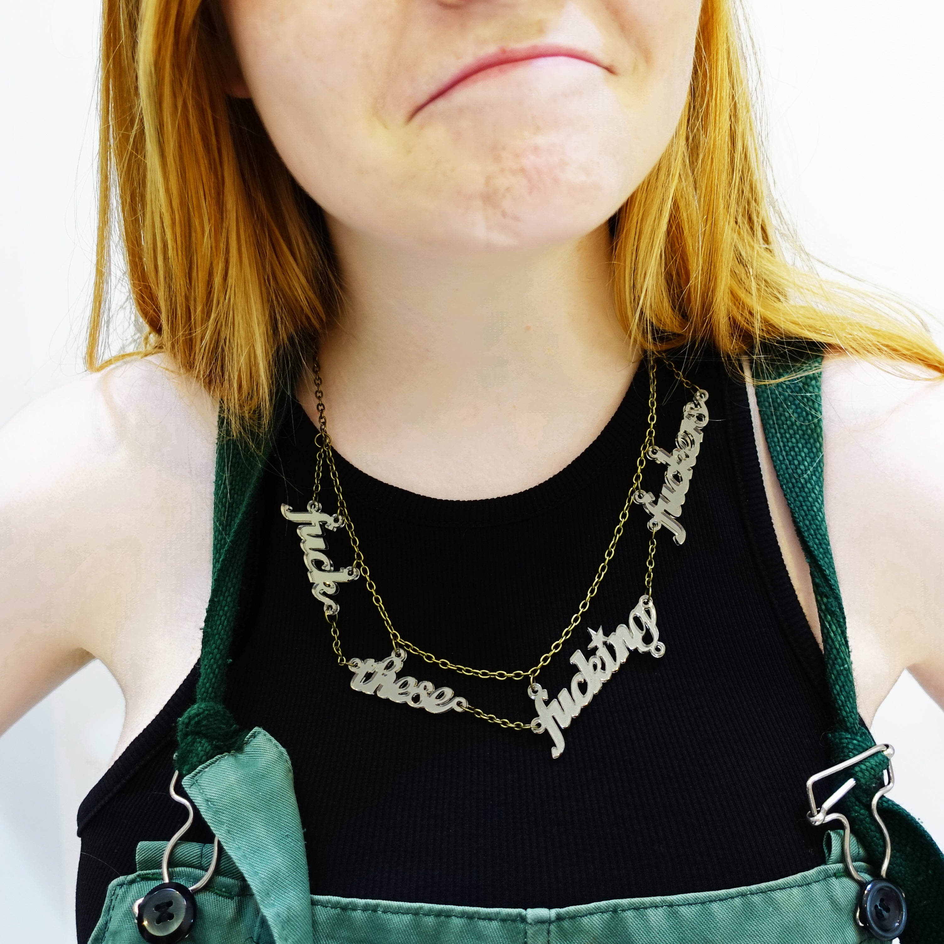 Eliza wears a bronze F*ck these F*cking F*ckers necklace.
