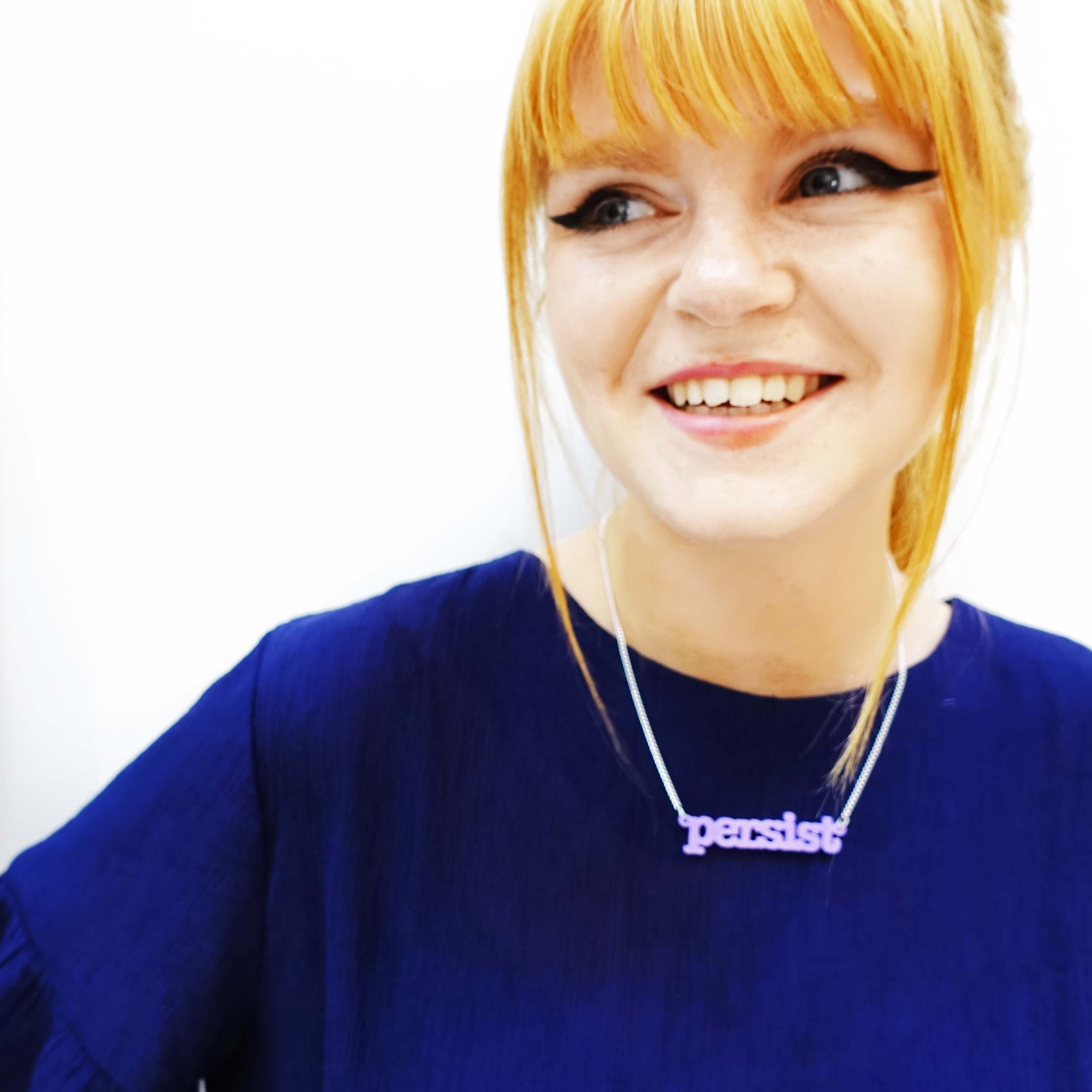Eliza wears a Parma violet typewriter font Persist necklace.
