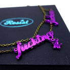 A close up of the F*ck these F*cking F*ckers necklace in purple mirror.