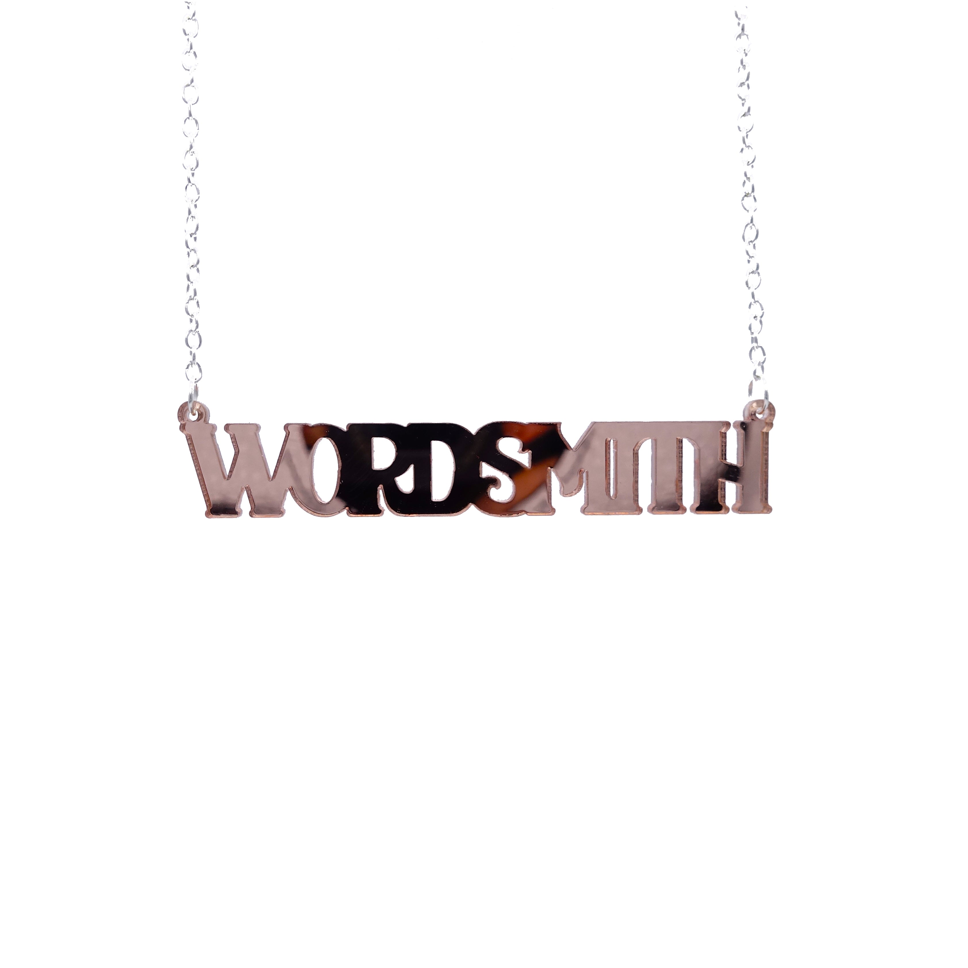 A necklace that says 'Wordsmith' in rose gold mirror, shown hanging against a white background.