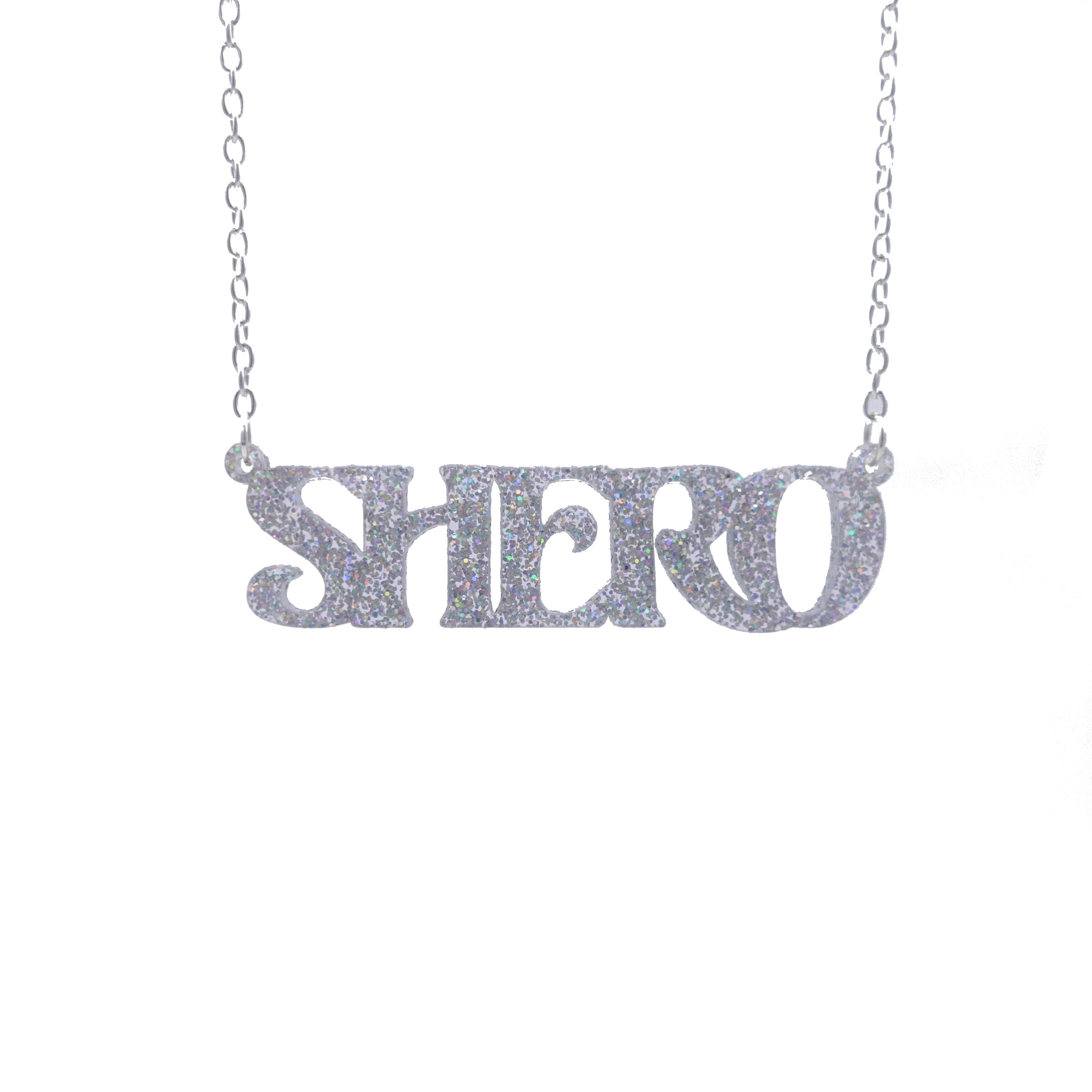 Silver glitter Shero necklace hanging against a white background.