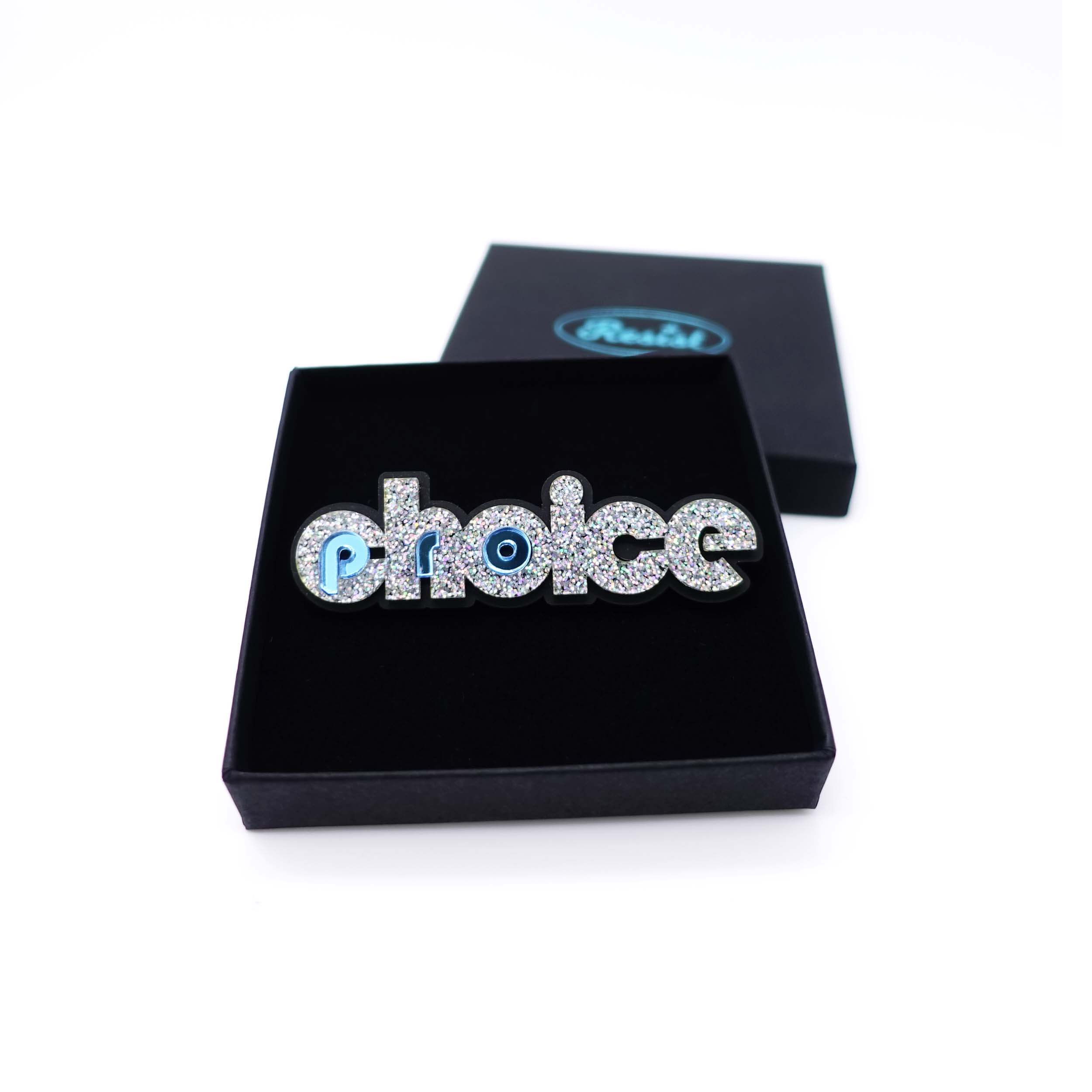 Iridescent silver glitter and sky mirror Pro-choice brooch, designed by Sarah Day for Wear and Resist, shown in a gift box.