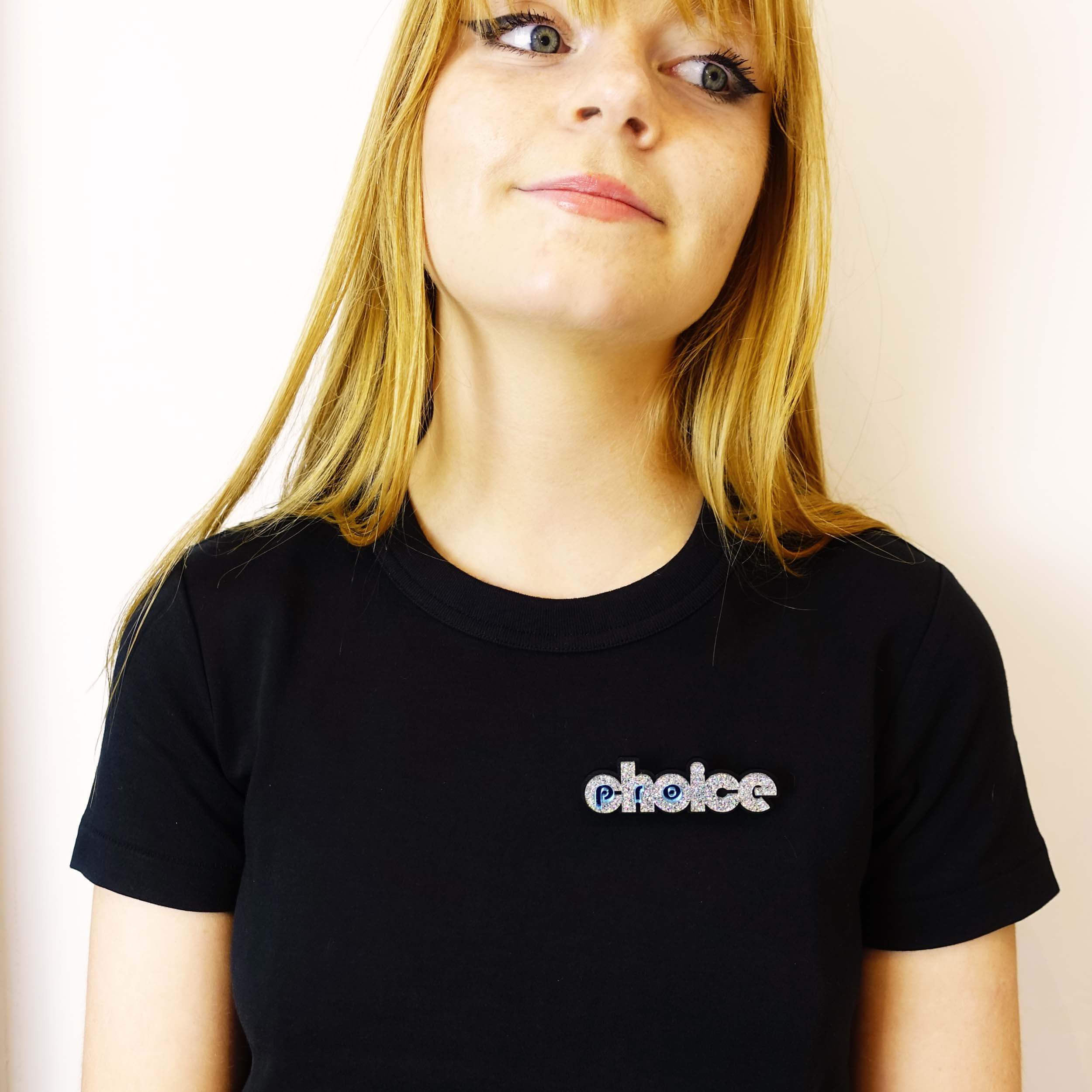 Model wears silver glitter pro-choice brooch, designed by Sarah Day for Wear and Resist.