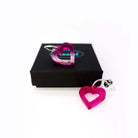 Small transparent hot pink love heart earrings shown one on a Wear and Resist gift box and one on the white background.