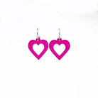 Small hot pink transparent love heart earrings shown against a white background.