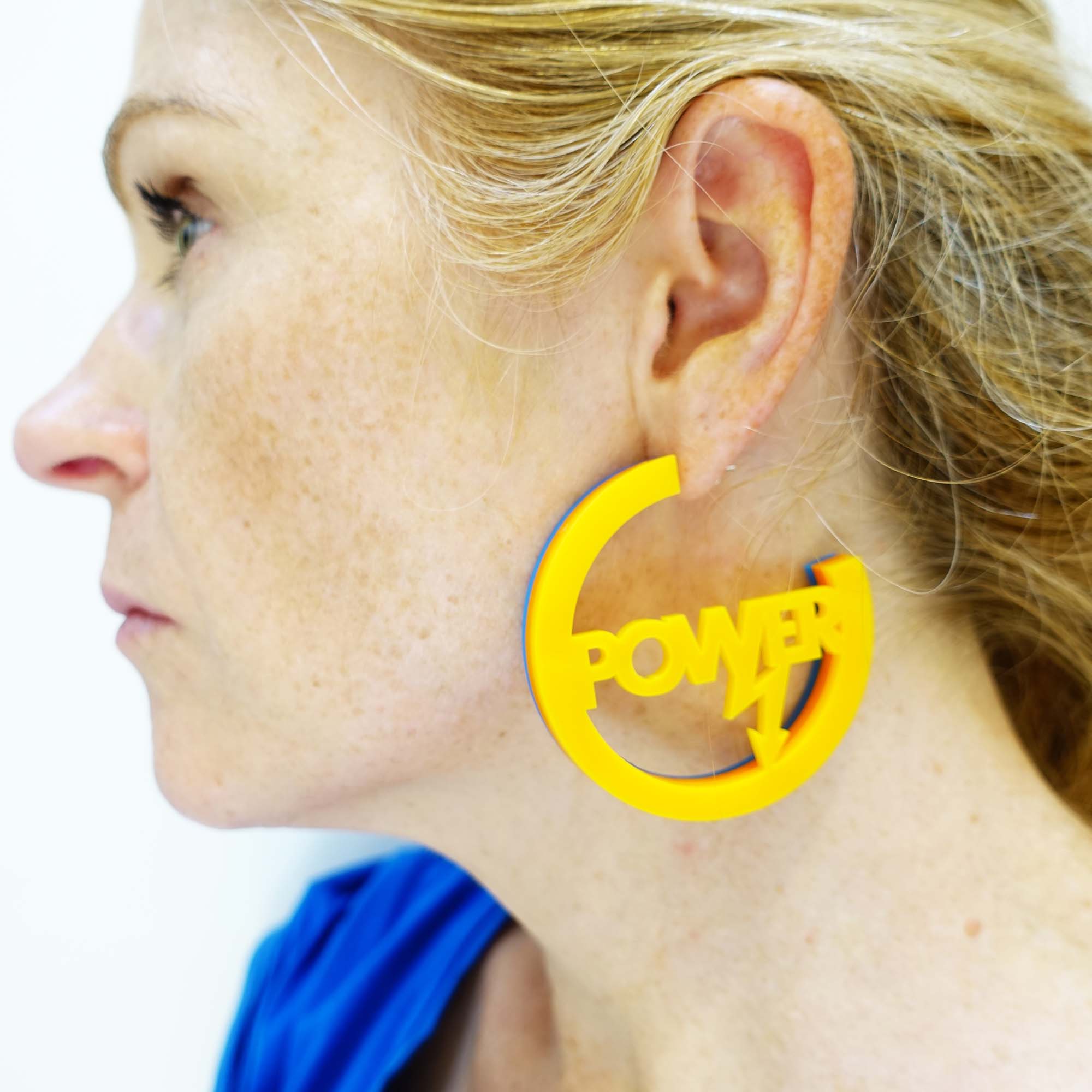 model wears Roller Disco sunflower yellow orange and blue Suffragette trio in Parma violet, white and avocado Mary Beard Women & Power earrings, statement hoops