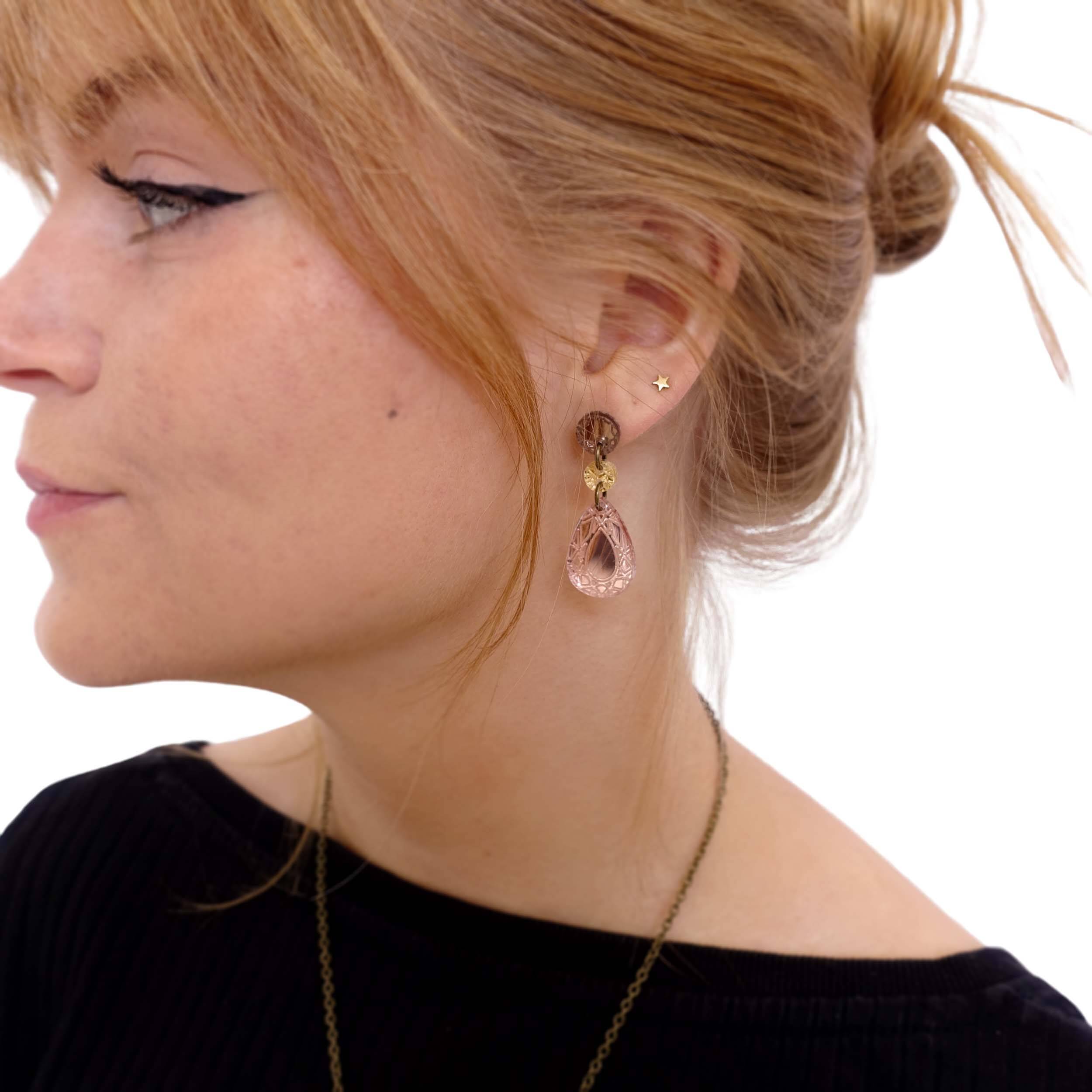 Eliza wears rose gold small jewel earrings.