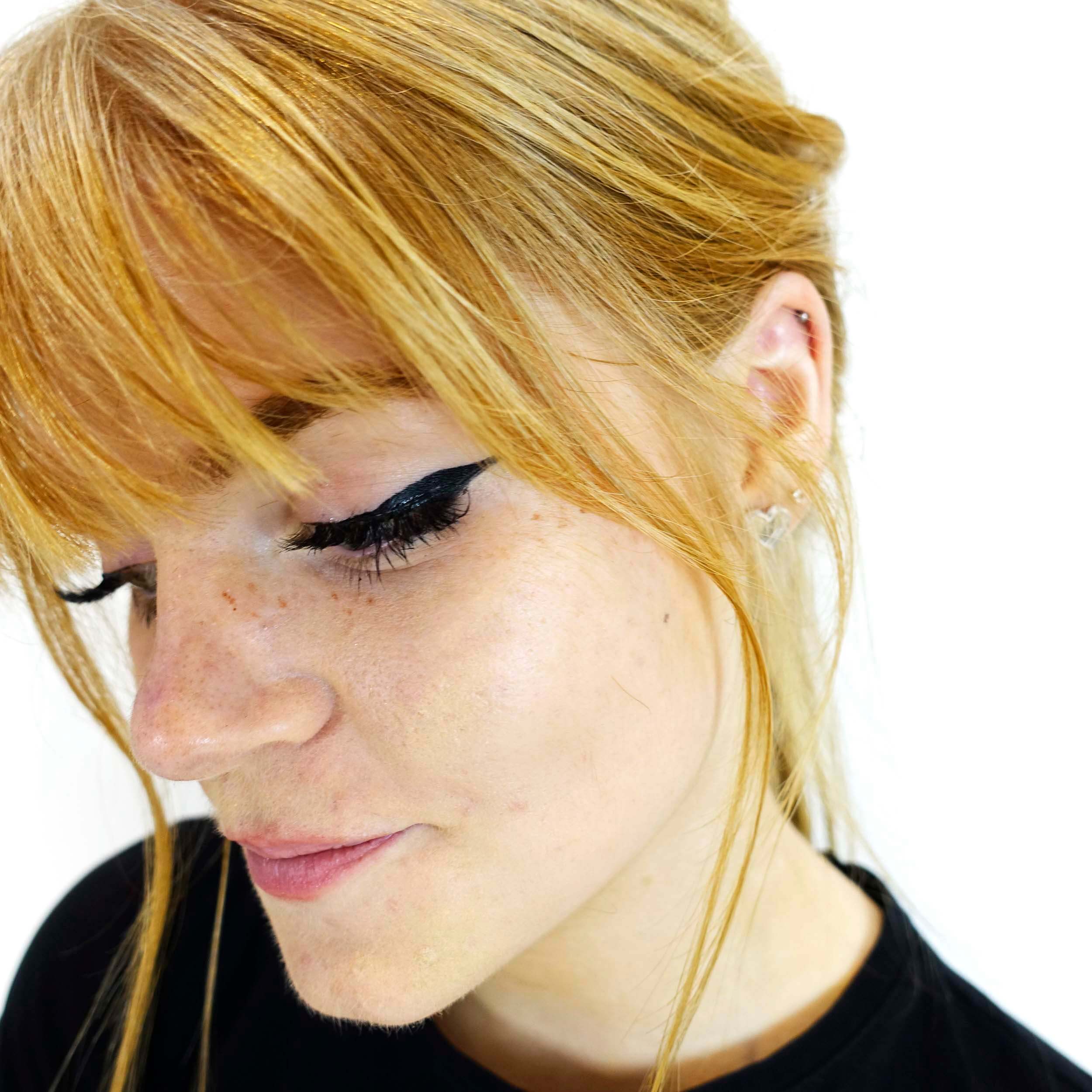 Eliza wears small silver heart stud earrings