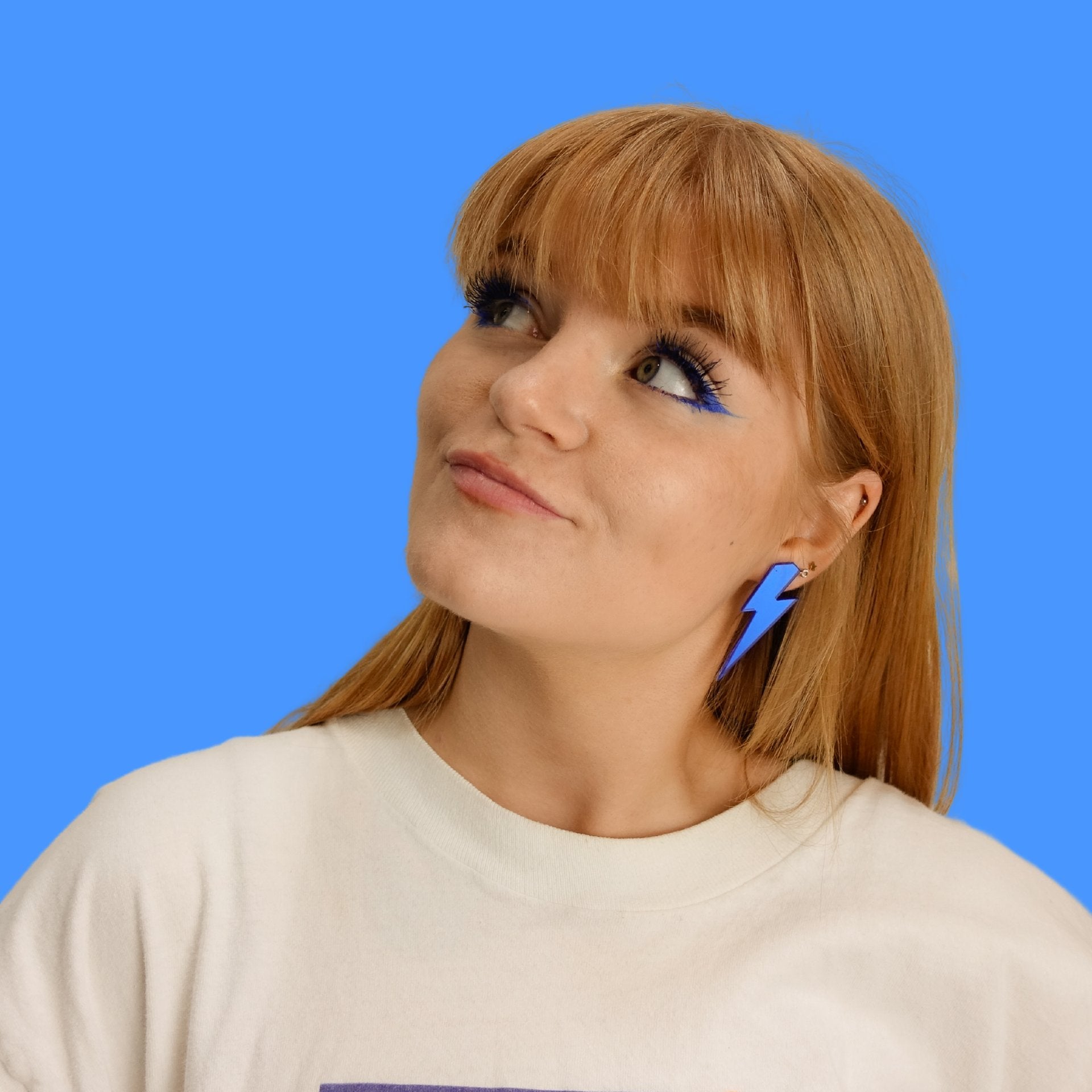 Eliza wears electric blue lightning bolt earrings