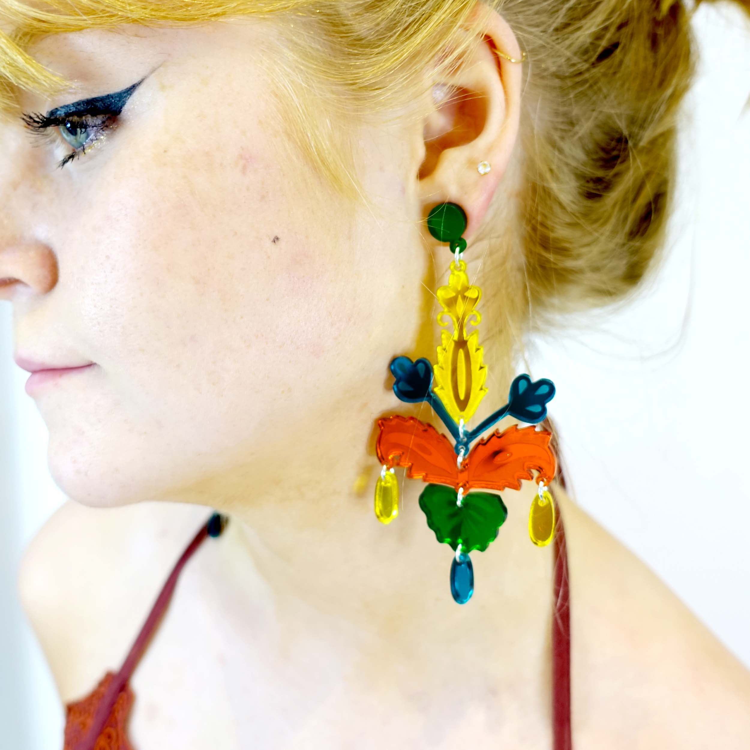 Model wears bright festival earrings in yellow, teal and fire mirror, perfect for partying at festivals, raves and garden parties! Designed by Sarah Day for Wear and Resist. Earrings for going out out. 