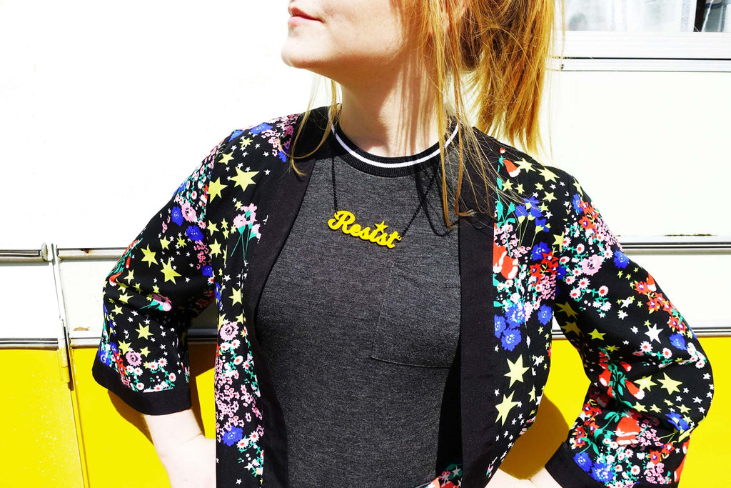 Model wears sunflower yellow Script Resist necklace designed by Sarah Day for Wear and Resist. 