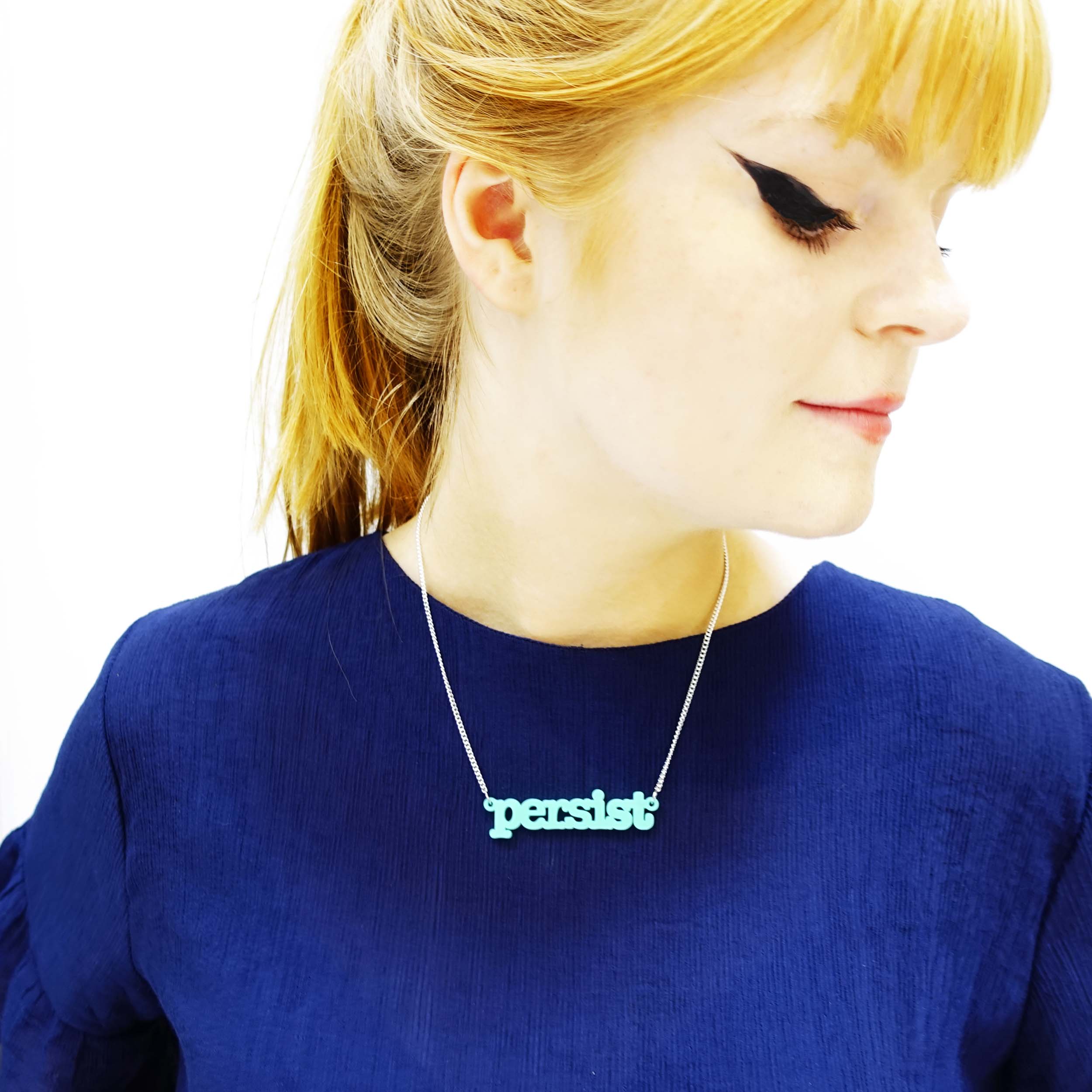 Model wears sea green typewriter persist necklace designed by Sarah Day for Wear and Resist. 