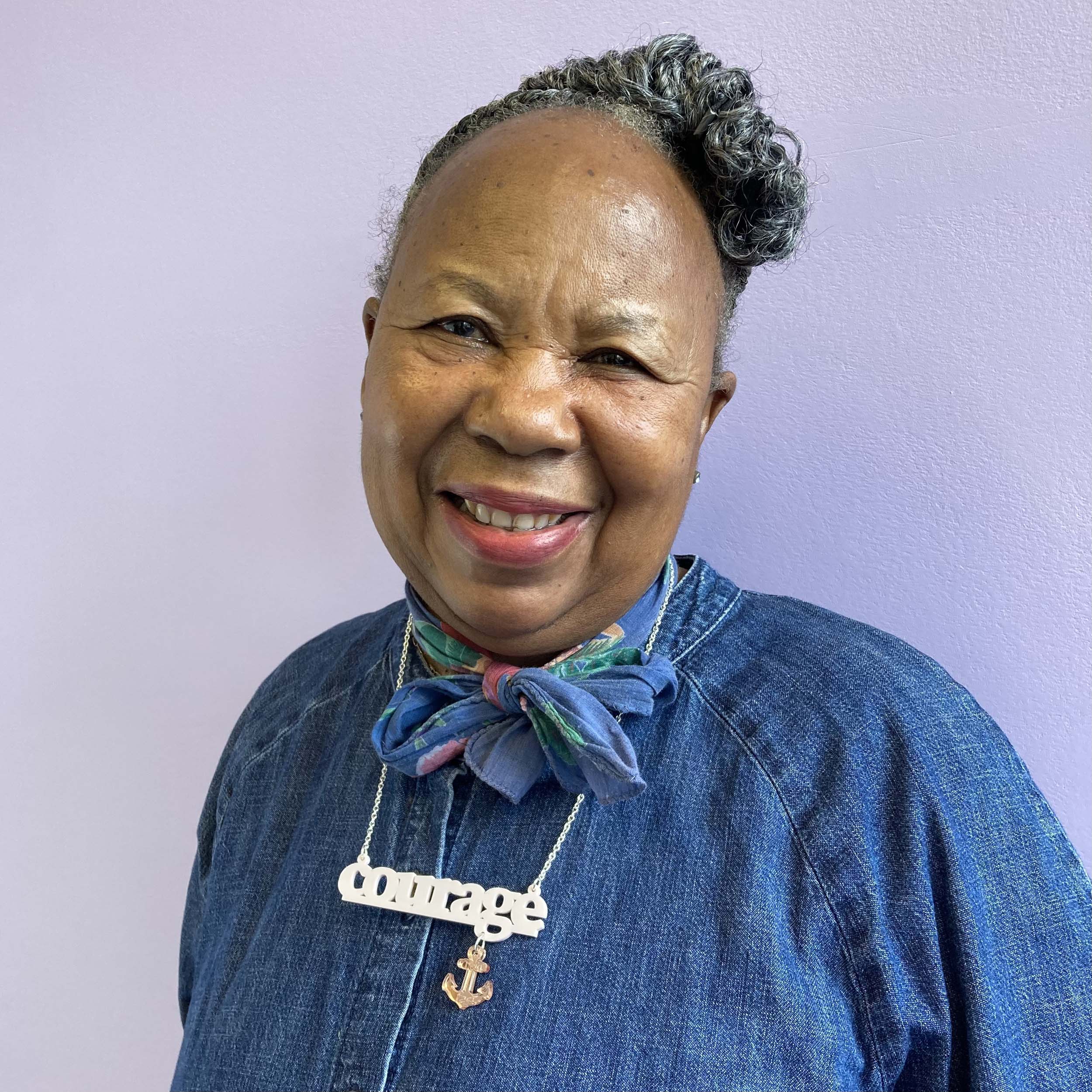 A member of Women for Refugee Women wearing a pink Courage necklace.