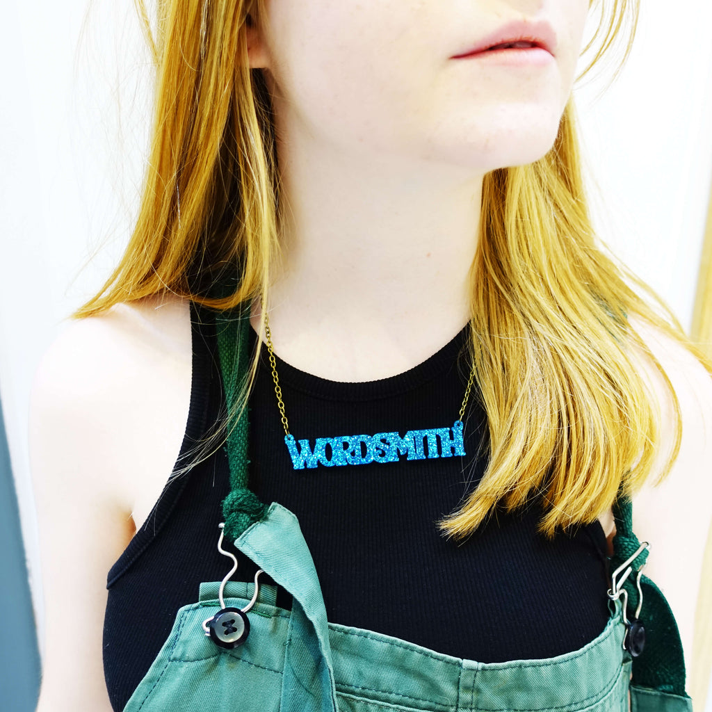 Eliza wears a glitter blue Wordsmith necklace