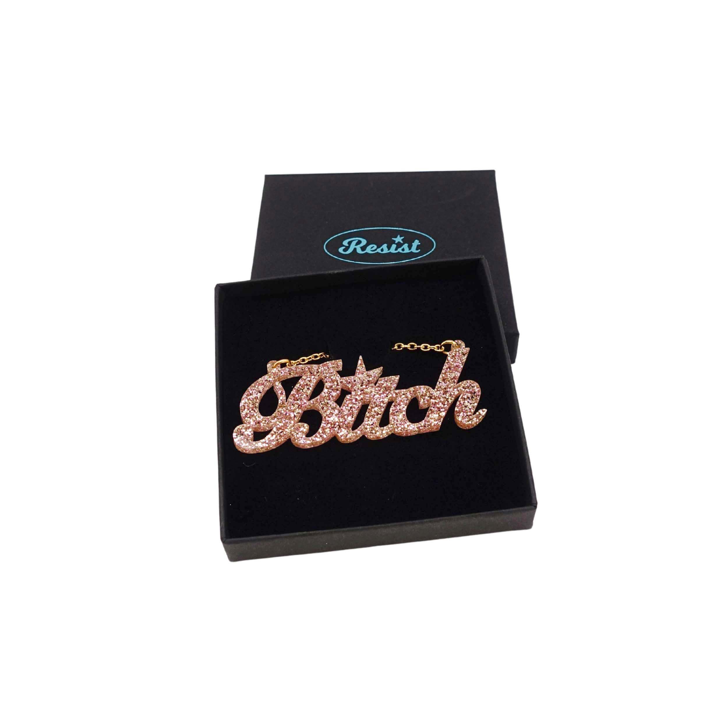 B*tch necklace in pink fizz glitter, shown in a Wear and Resist gift box. £2 goes to Bloody Good Period. 