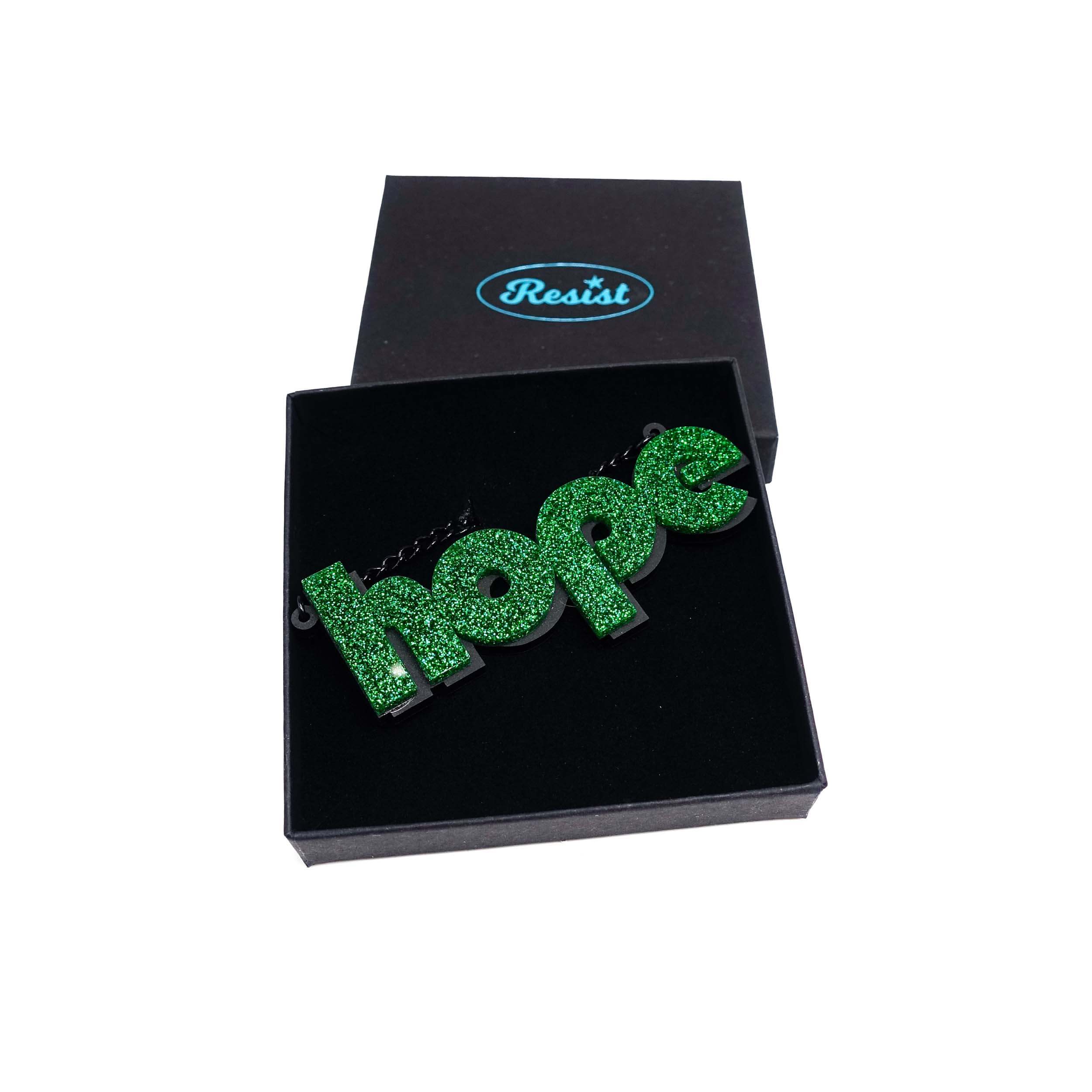 Hope statement necklace in green glitter, shown in a Wear and Resist gift box.