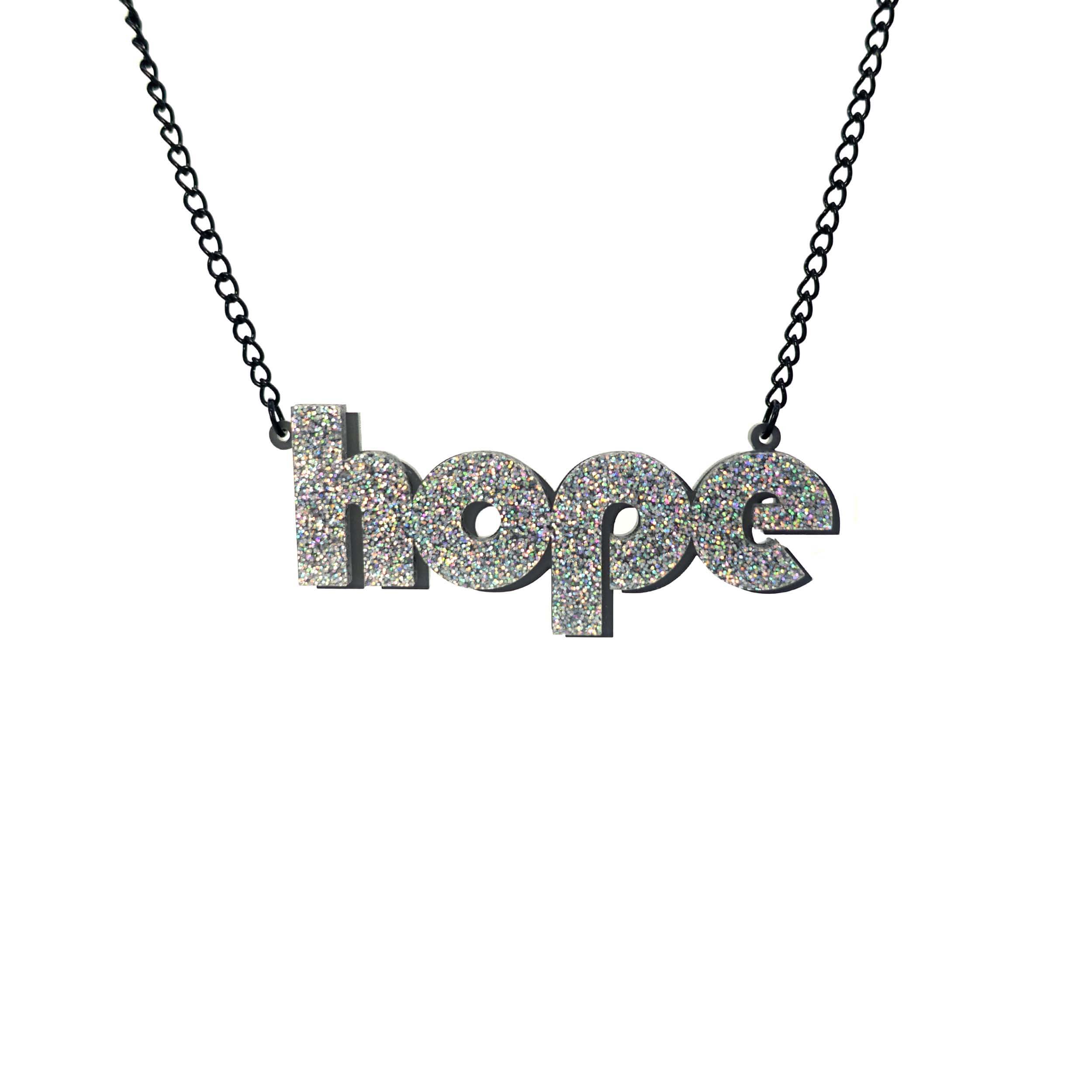 Hope statement necklace in silver glitter with backing layer that works as a drop shadow, shown hanging against a white background.