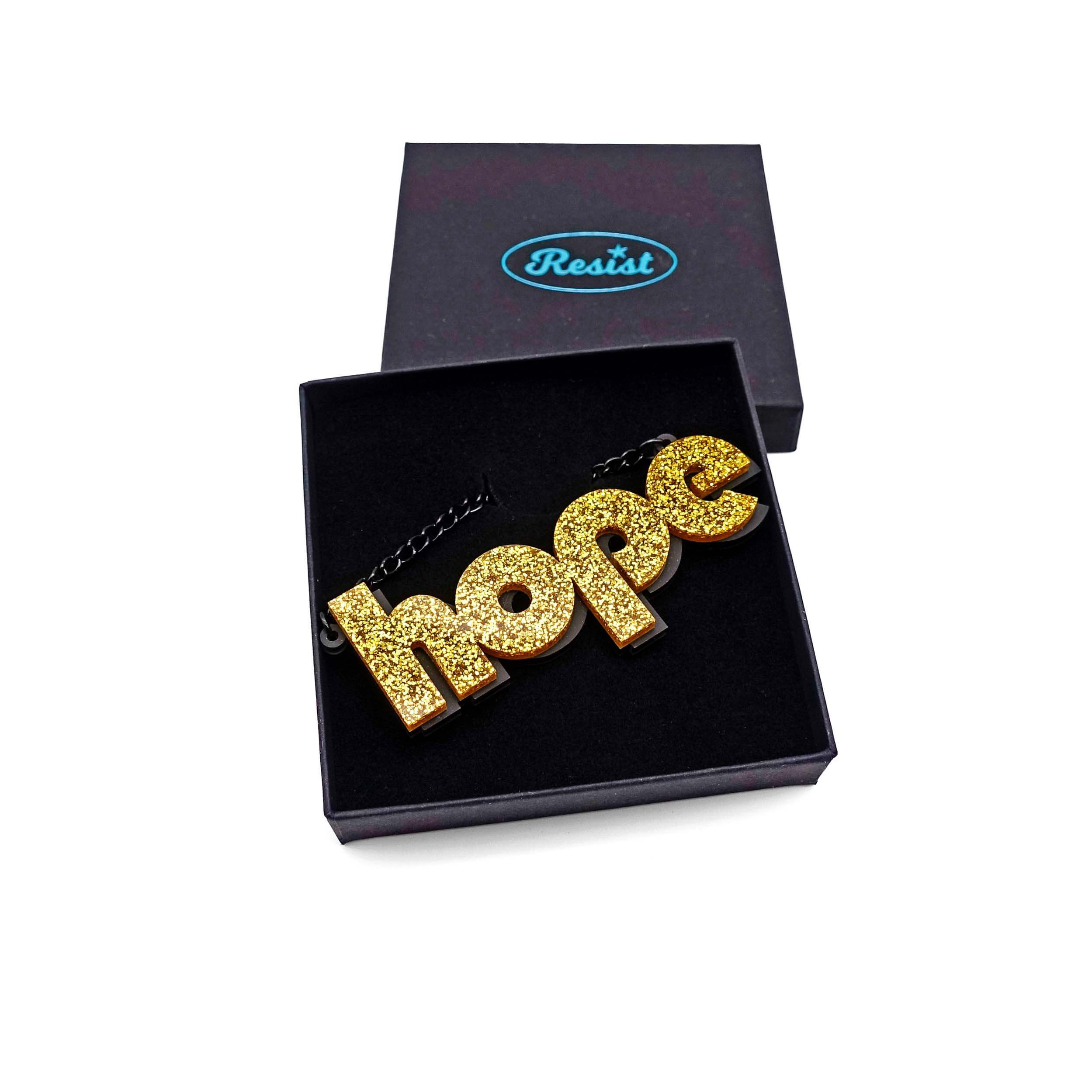 Hope statement necklace in ultra gold glitter, shown in a Wear and Resist gift box.